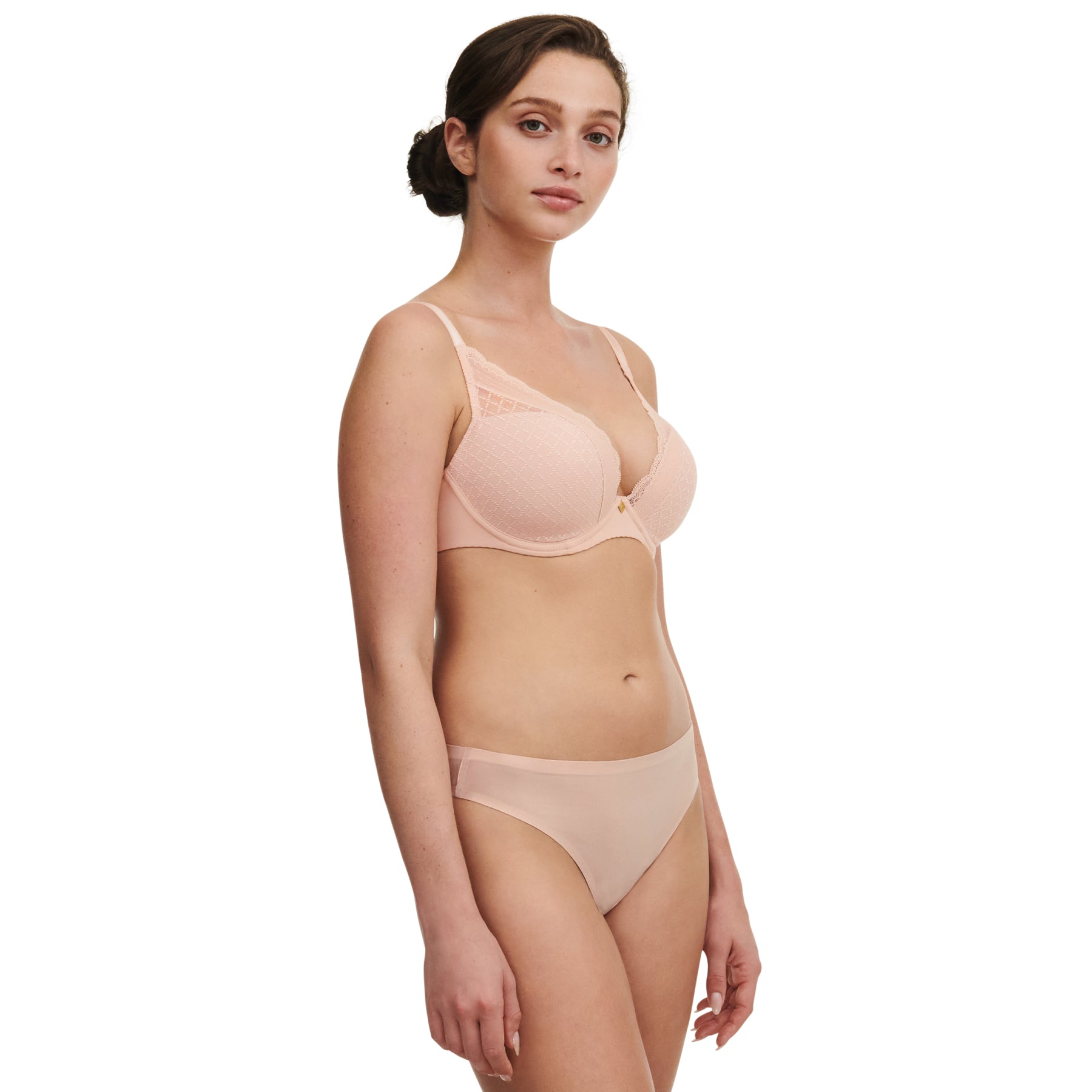Three-quarter view of model wearing nude rose plunge bra with lace trim and matching nude thong.