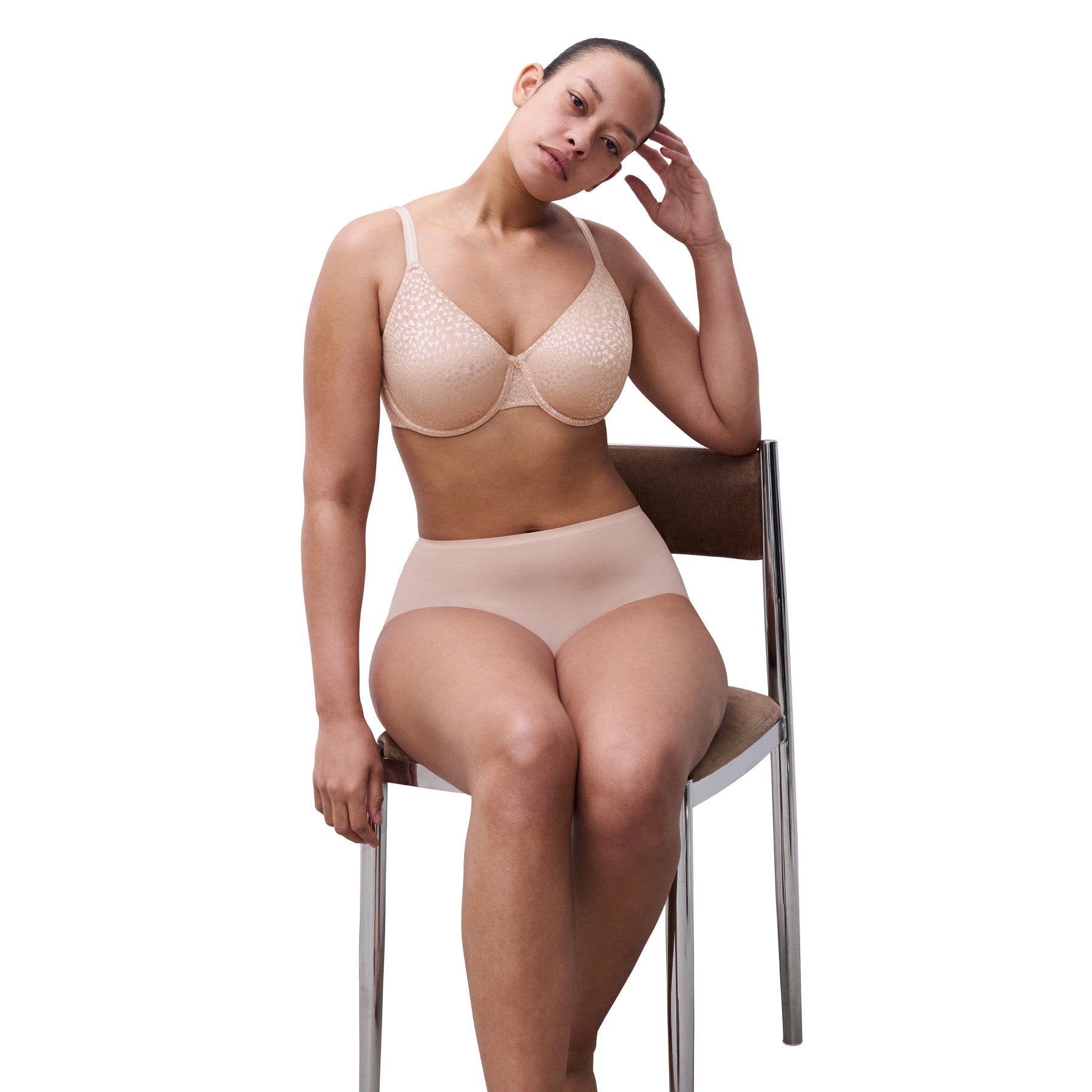 Woman seated in matching soft pink minimizer bra and seamless brief, showcasing everyday comfort and fit.