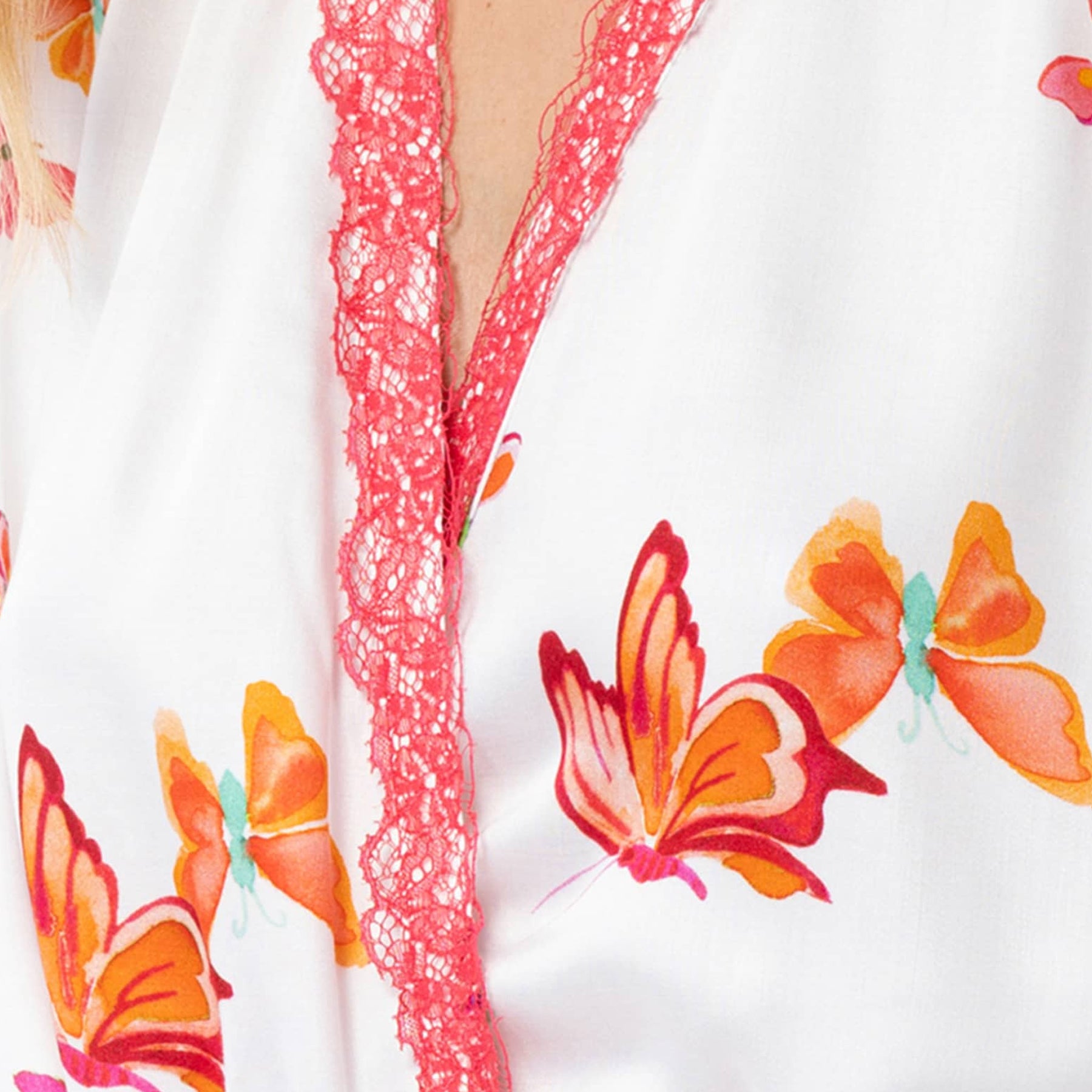 Close-up of white robe with orange butterfly print and coral pink lace trim detail