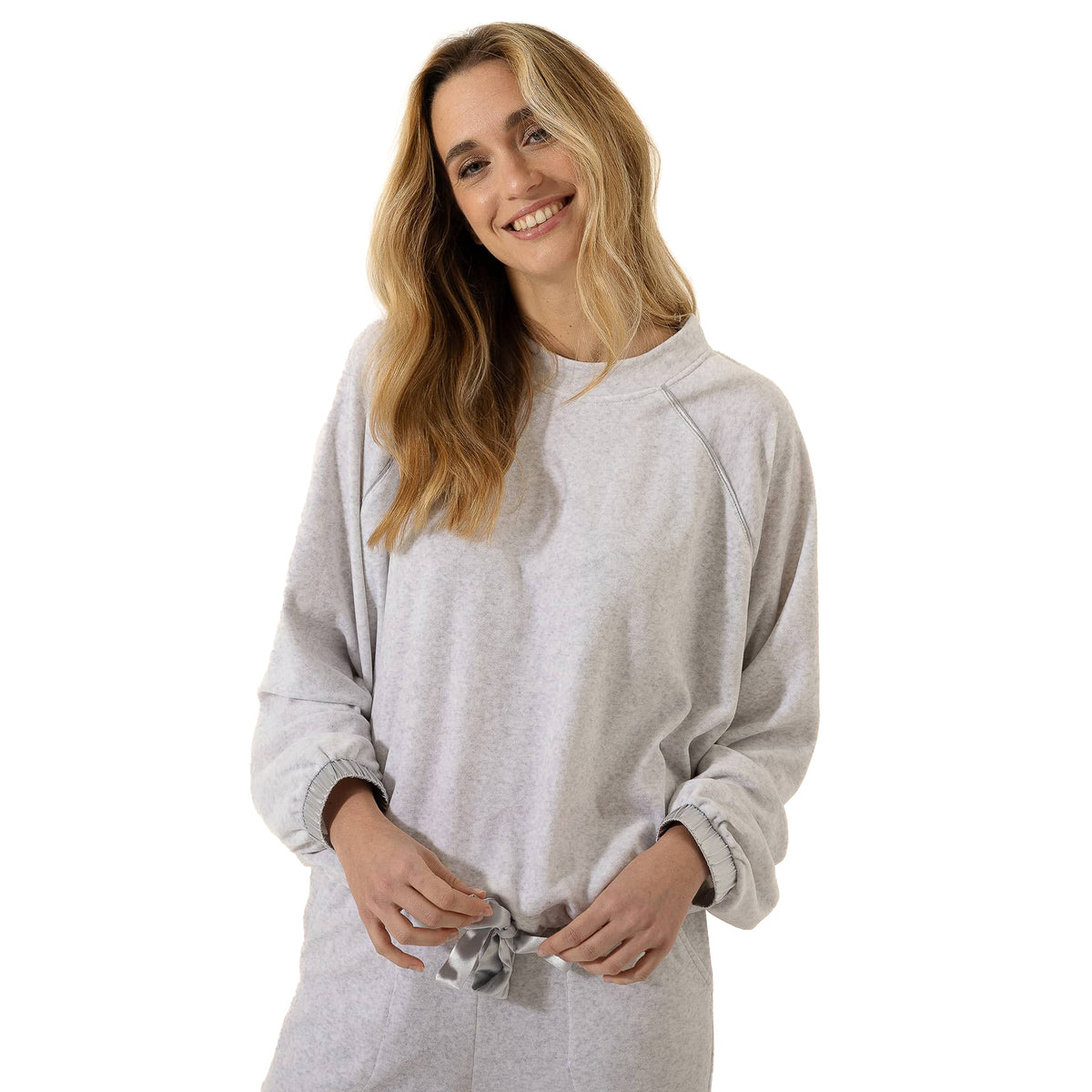 Close-up of woman wearing a light grey lounge top with a relaxed fit, raglan sleeves, elastic cuffs, and satin tie detail at the hem.