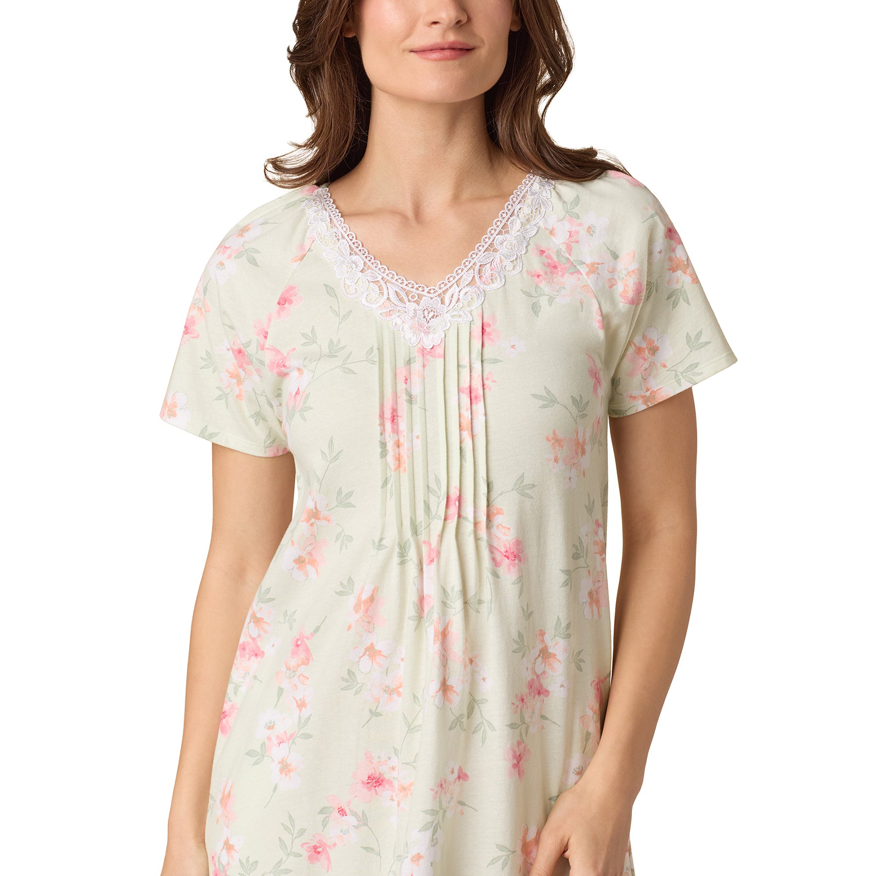 Close-up of lace-trimmed V-neck and soft pink floral pattern on green background