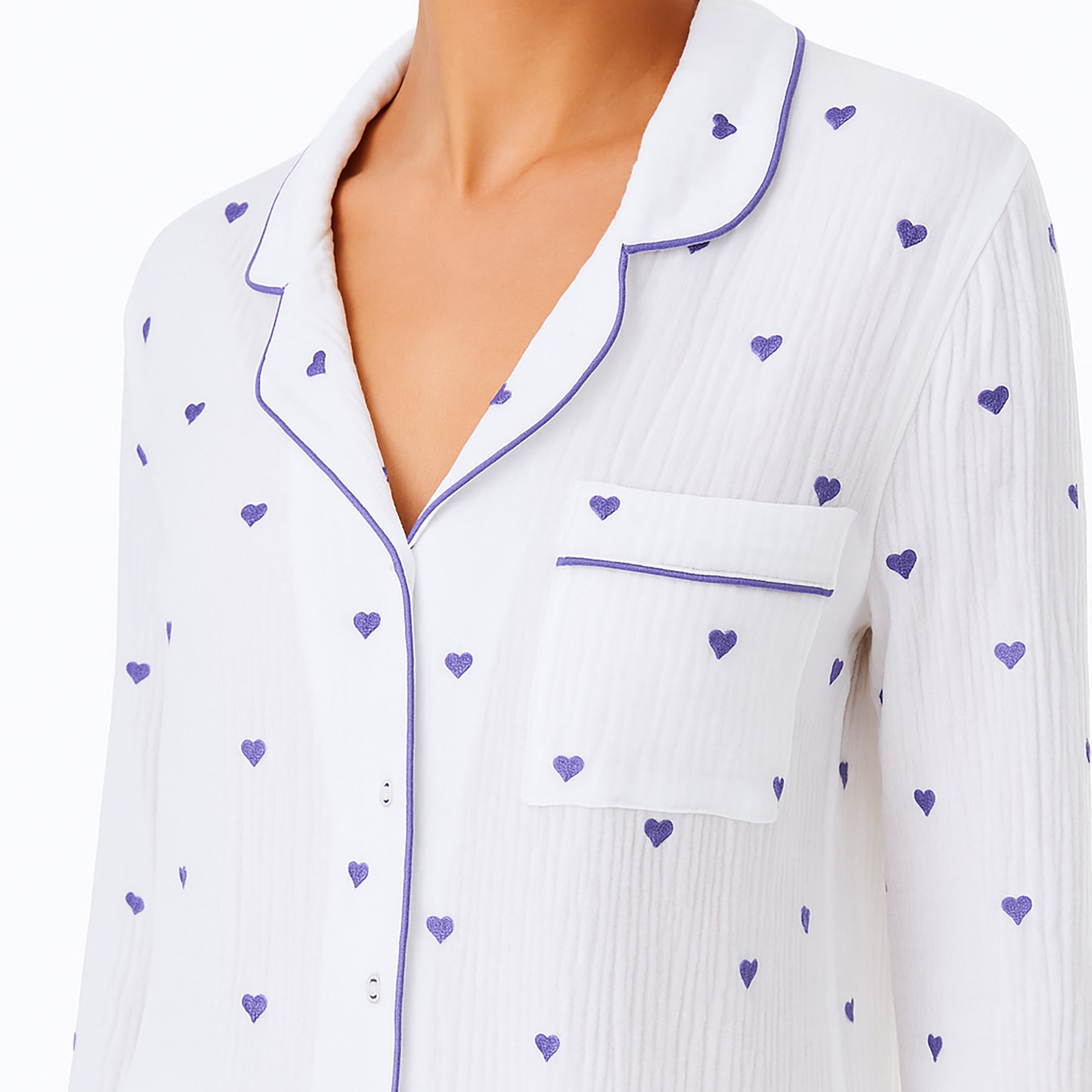 Model wearing white gauze cotton pajama top with purple embroidered hearts and matching piping – long sleeve sleep shirt with chest pocket and button front