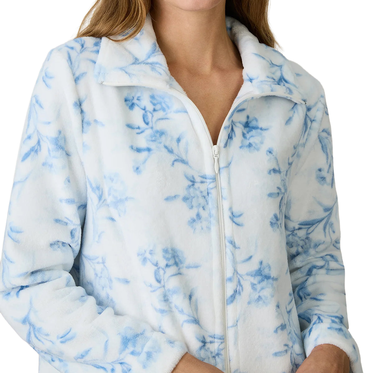 Close-up of a plush white fleece robe with a delicate blue floral print, showing the soft fabric texture, fold-over collar and front zipper.