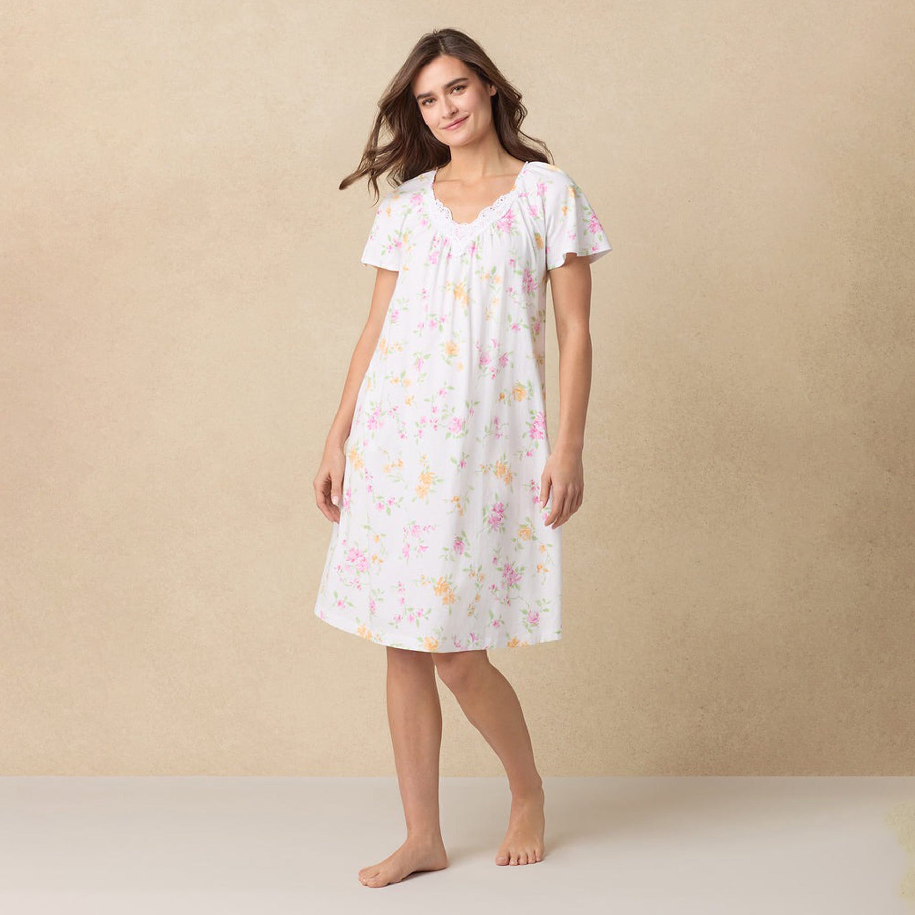 Woman walking in a white floral nightgown with lace neckline and soft flutter sleeves.