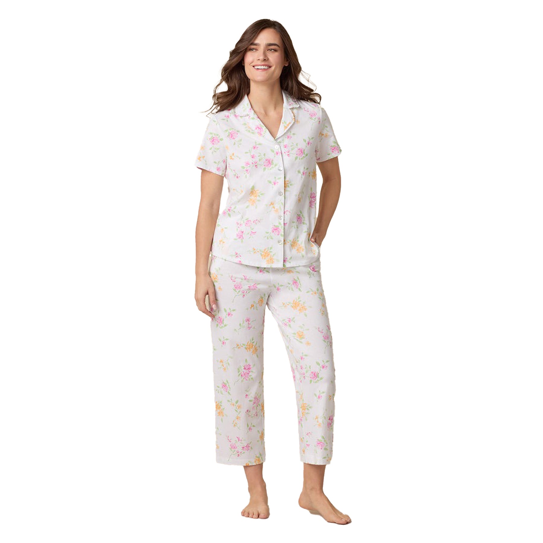Woman wearing a short-sleeve floral pajama set with cropped pants in white and pastel print.