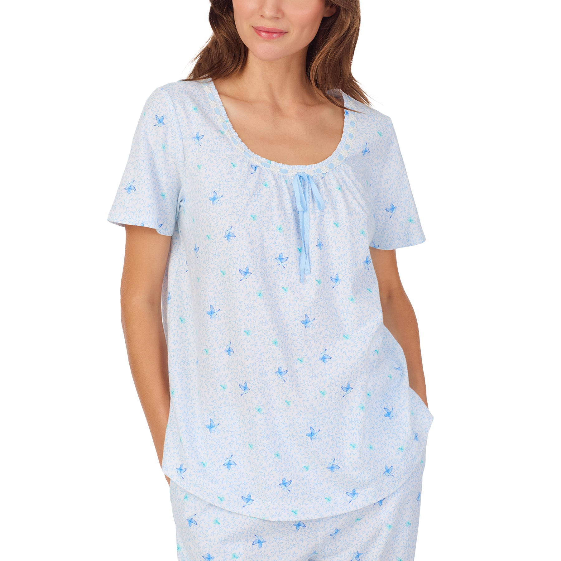 Woman wearing a light blue floral-print cotton pajama set with short sleeves and a scoop neckline featuring a bow detail.