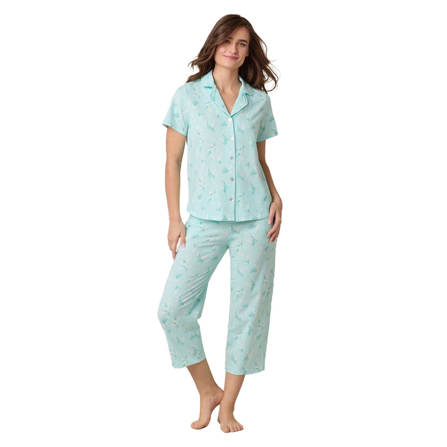 Woman in pastel green floral pyjama set with relaxed fit and collared short-sleeve top.