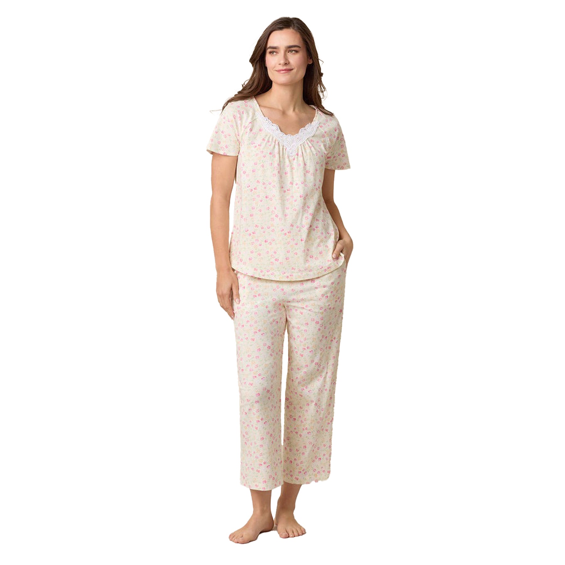Woman wearing short-sleeve floral pajama set with lace-trimmed neckline and full-length pants.
