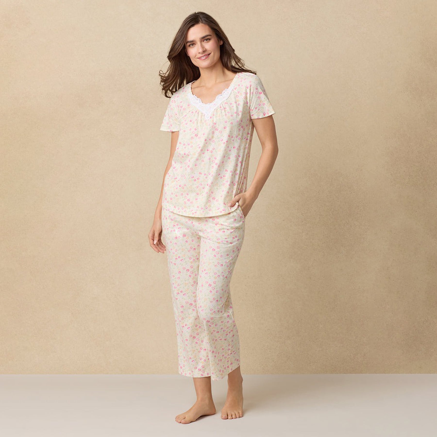 Woman wearing the full floral pajama set, smiling with hands in pockets.
