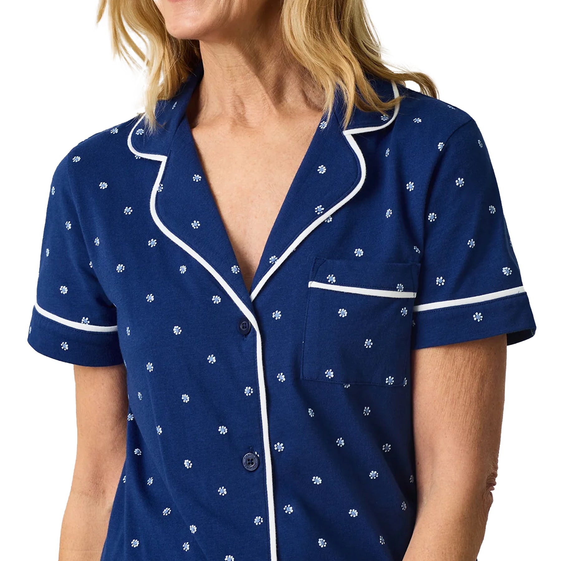 Close-up of navy blue pyjama top with white ditsy floral print, notched collar and chest pocket.