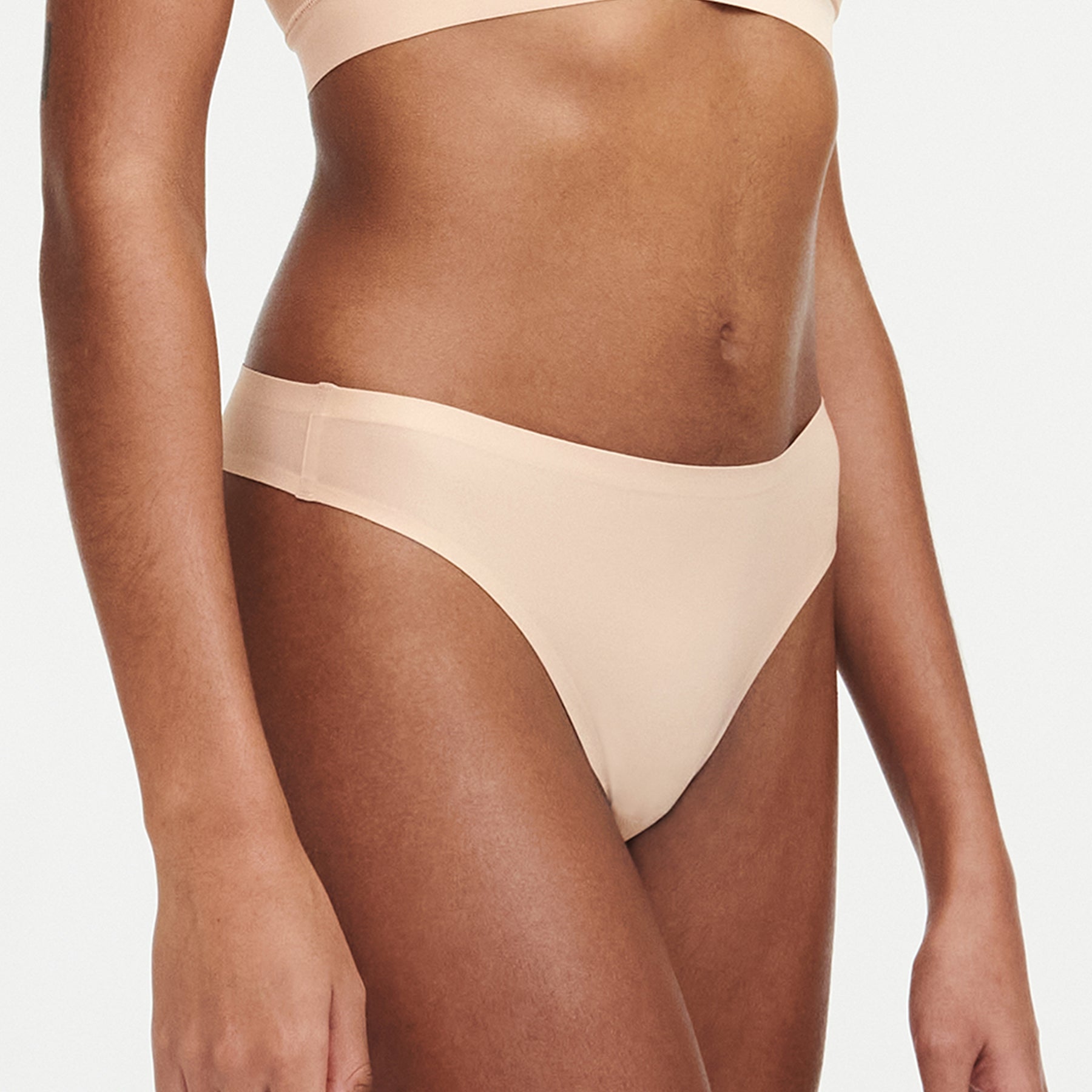 Chantelle Soft Stretch thong in golden beige - seamless high-cut invisible underwear. Side view on model.