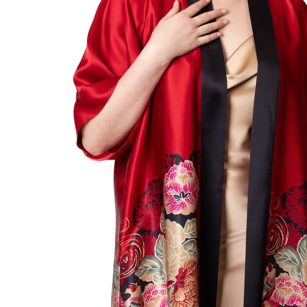 Close-up of Christine Crimson Moon Kimono highlighting the lustrous red satin, contrasting black shawl trim, and intricate pink and gold floral design.