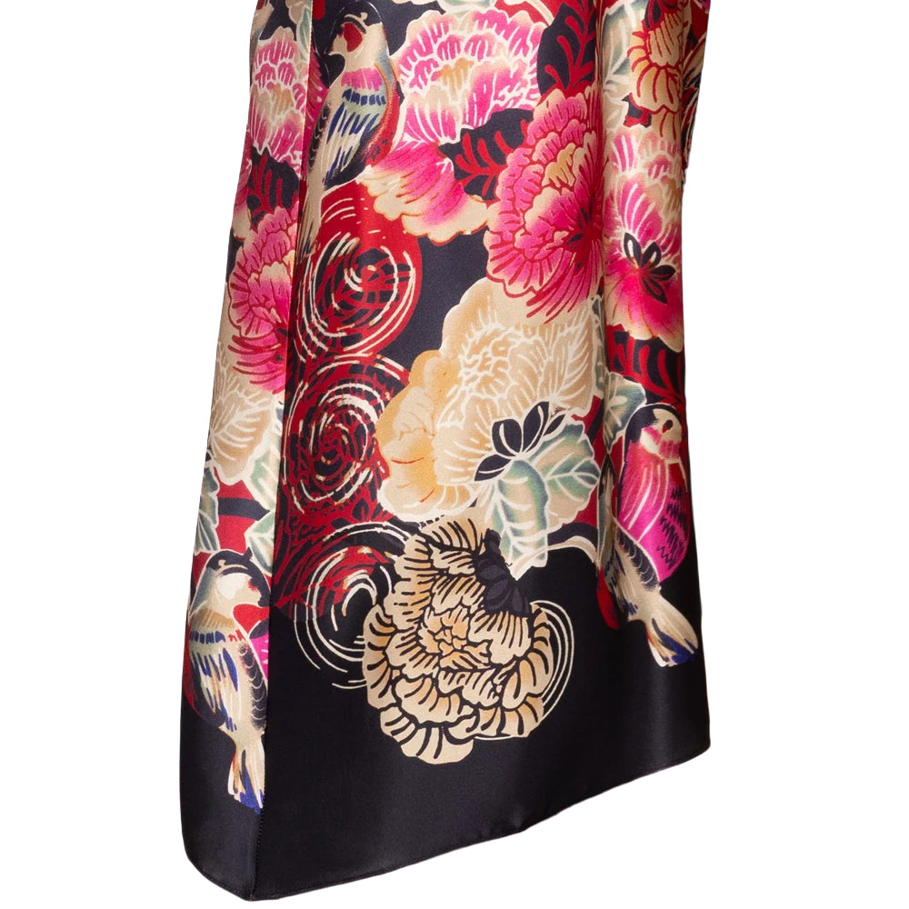 Close-up of Christine Crimson Moon Kimono featuring an elaborate floral and bird print in pink, gold, cream, and green against a black satin background.