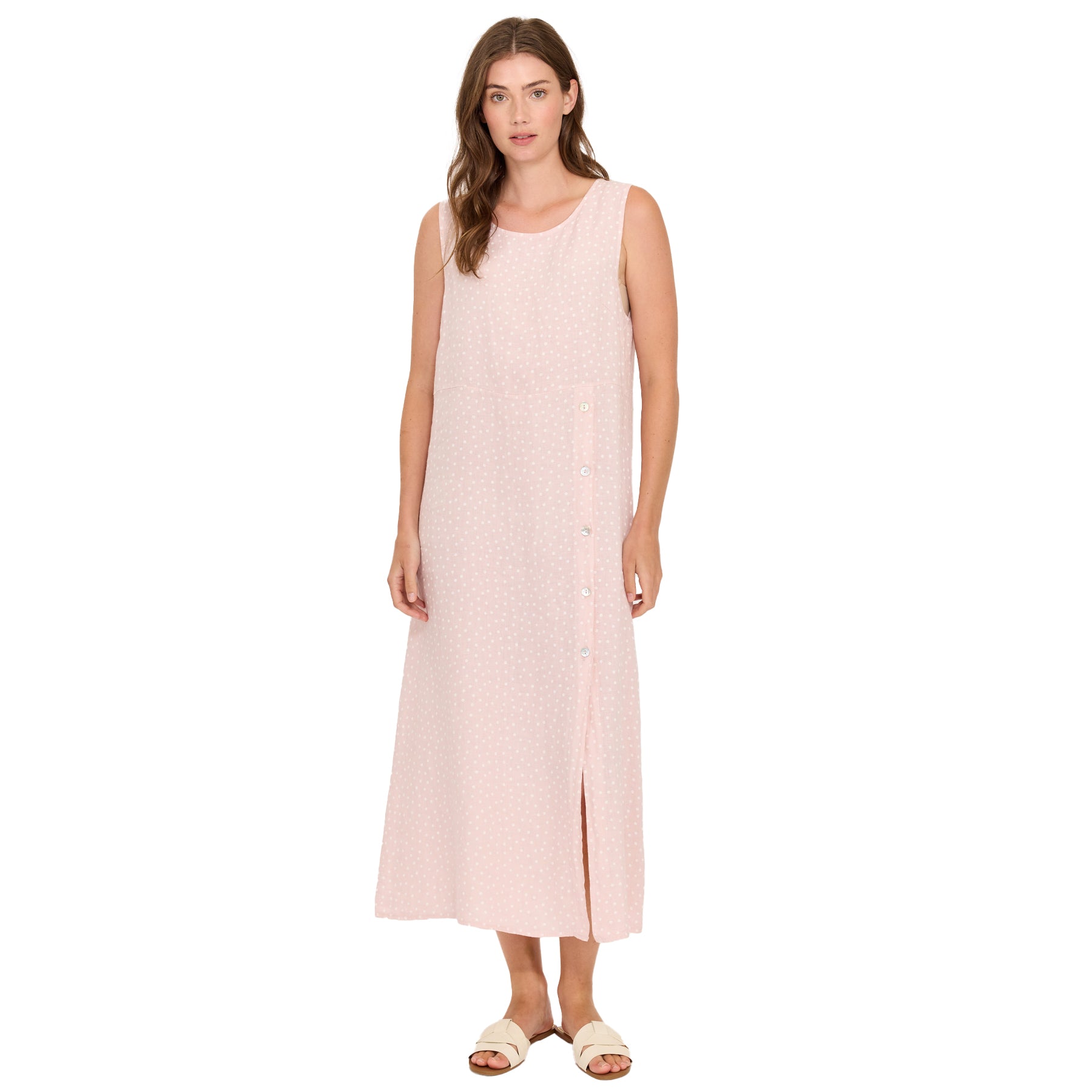 Woman wearing blush pink polka dot sleeveless midi dress with side buttons and front slit