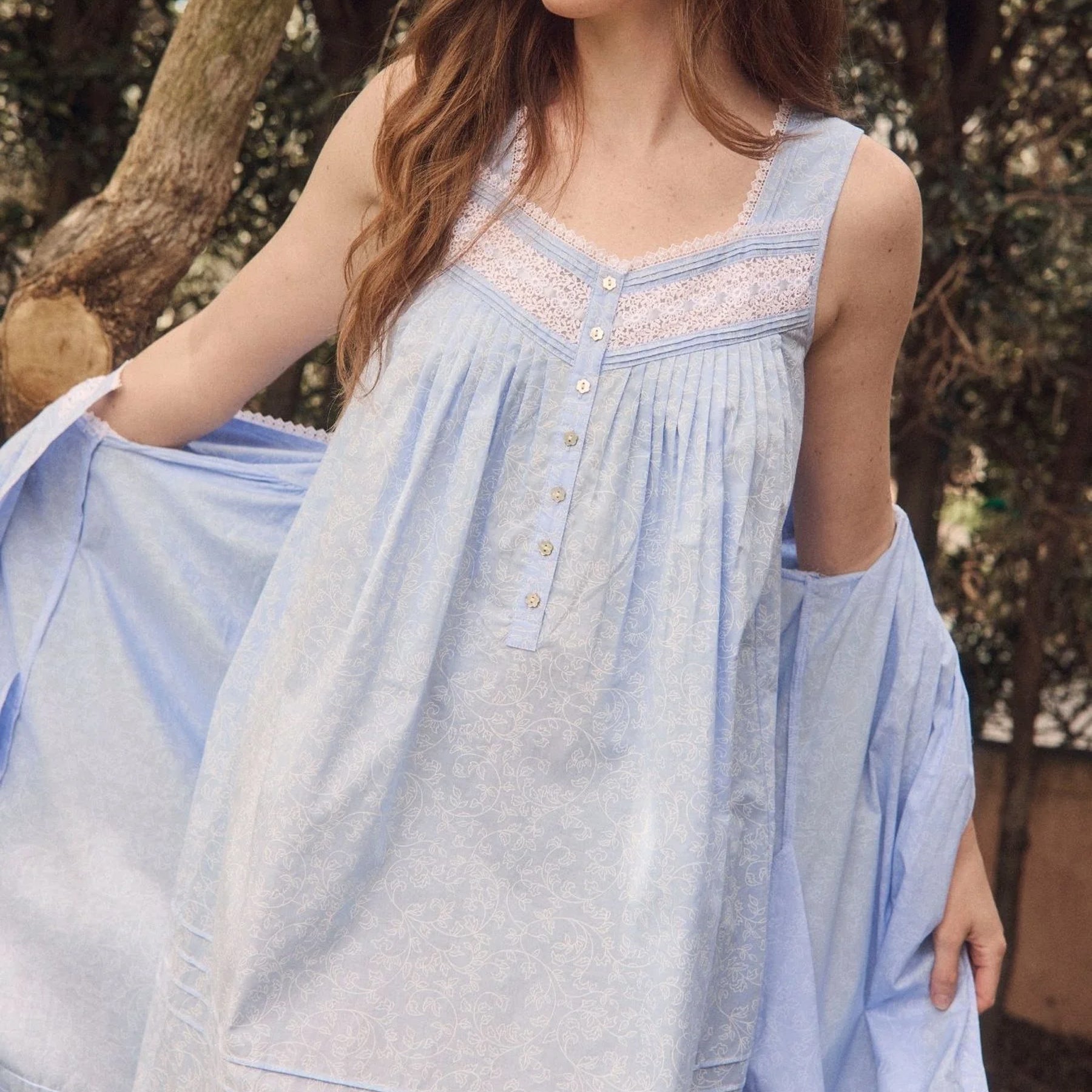 Close-up lifestyle image of blue cotton nightgown with delicate lace trim, button front and soft gathered bodice