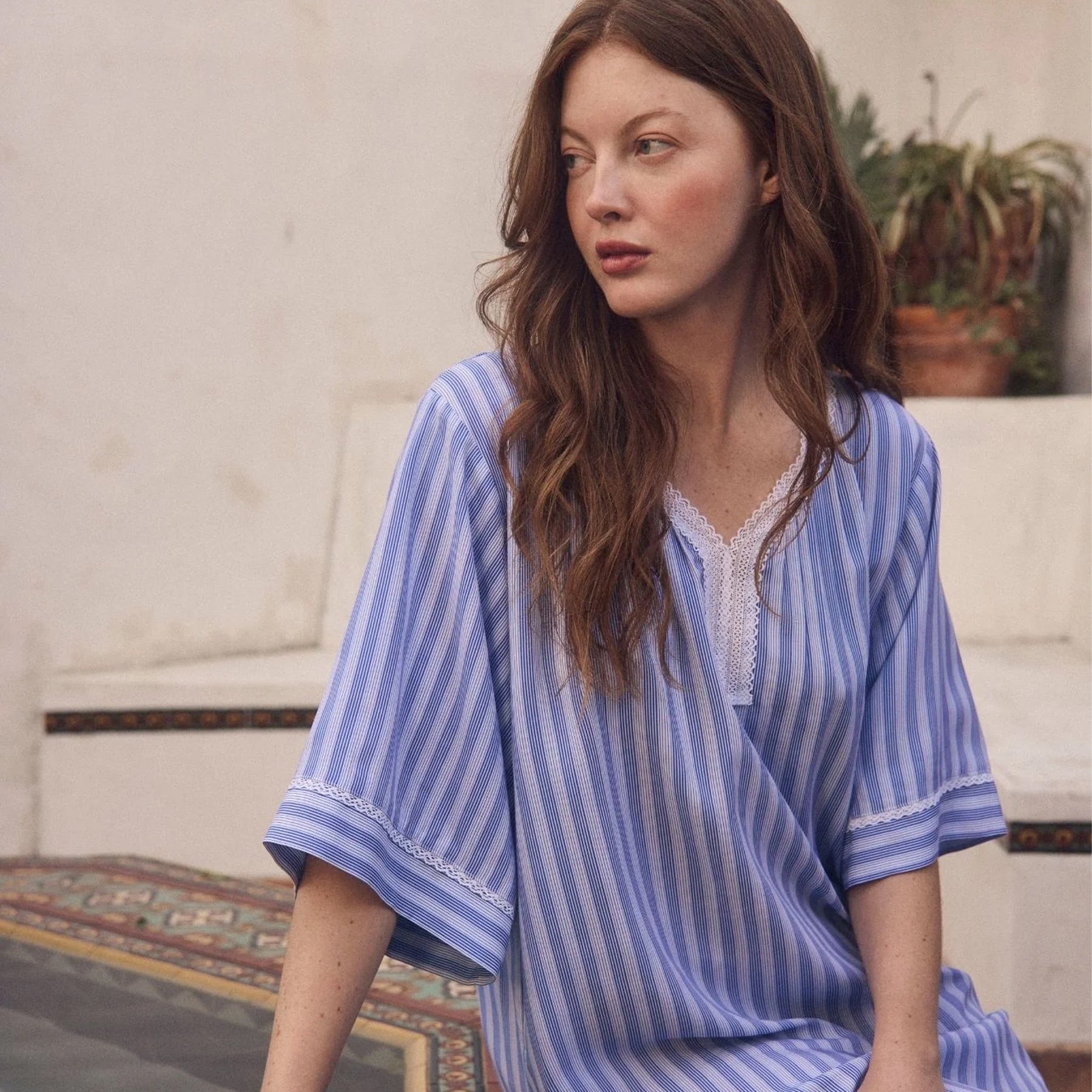 Close-up of blue striped cotton nightgown with white lace-trim neckline and relaxed fit, worn outdoors