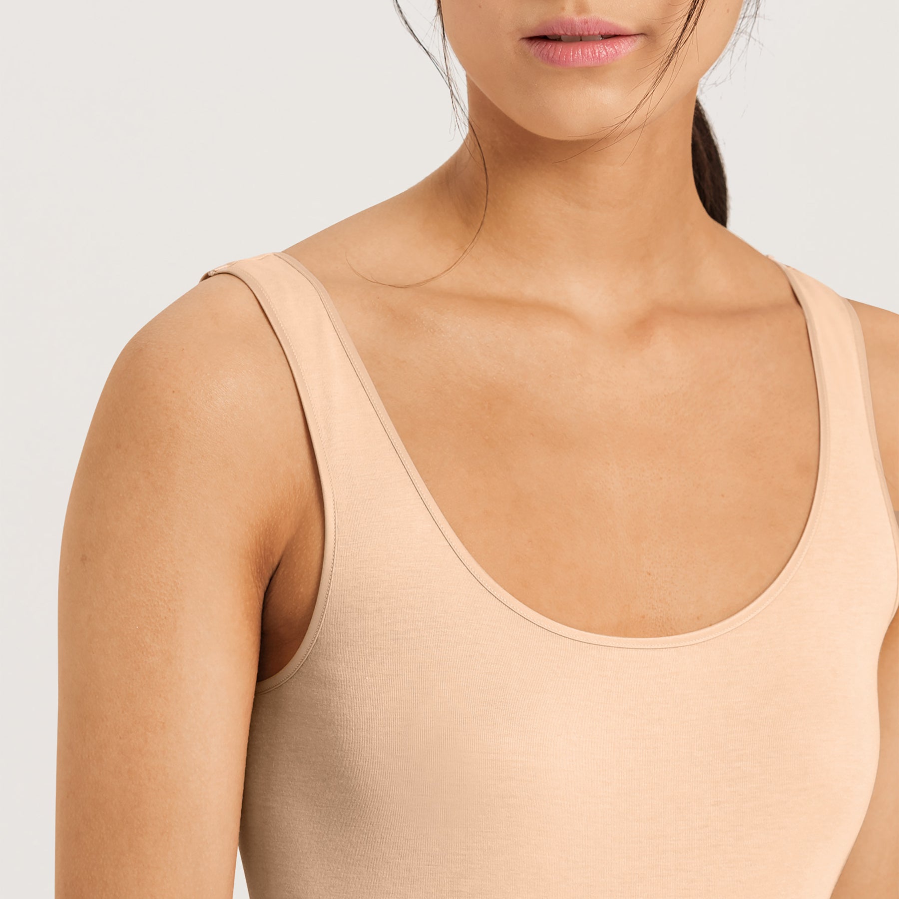 Close-up of scoop neckline and seamless shoulder design on the Hanro Cotton Seamless Tank in Beige.