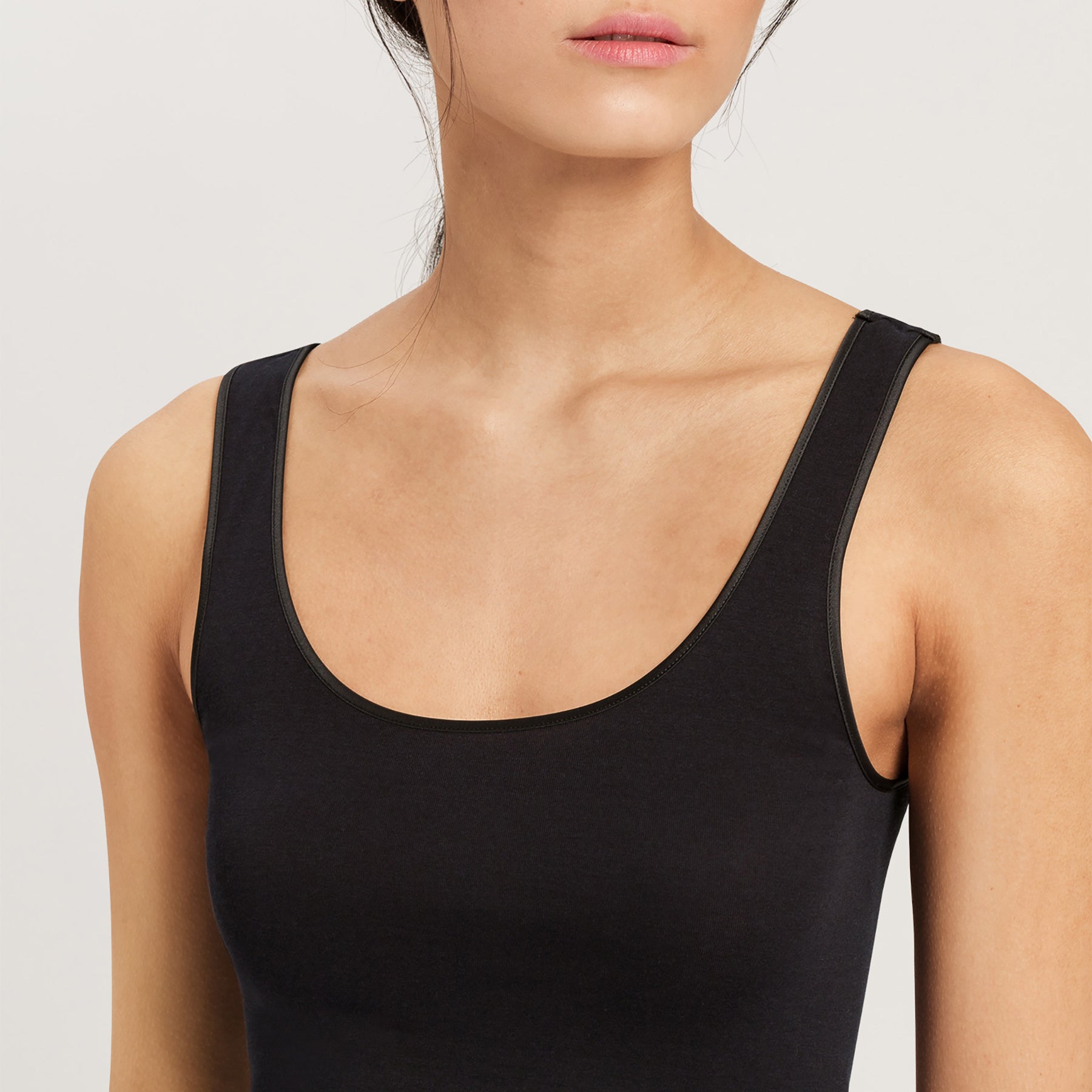 Close-up of scoop neckline and fine ribbed trim on the Hanro Cotton Seamless Tank in Black.
