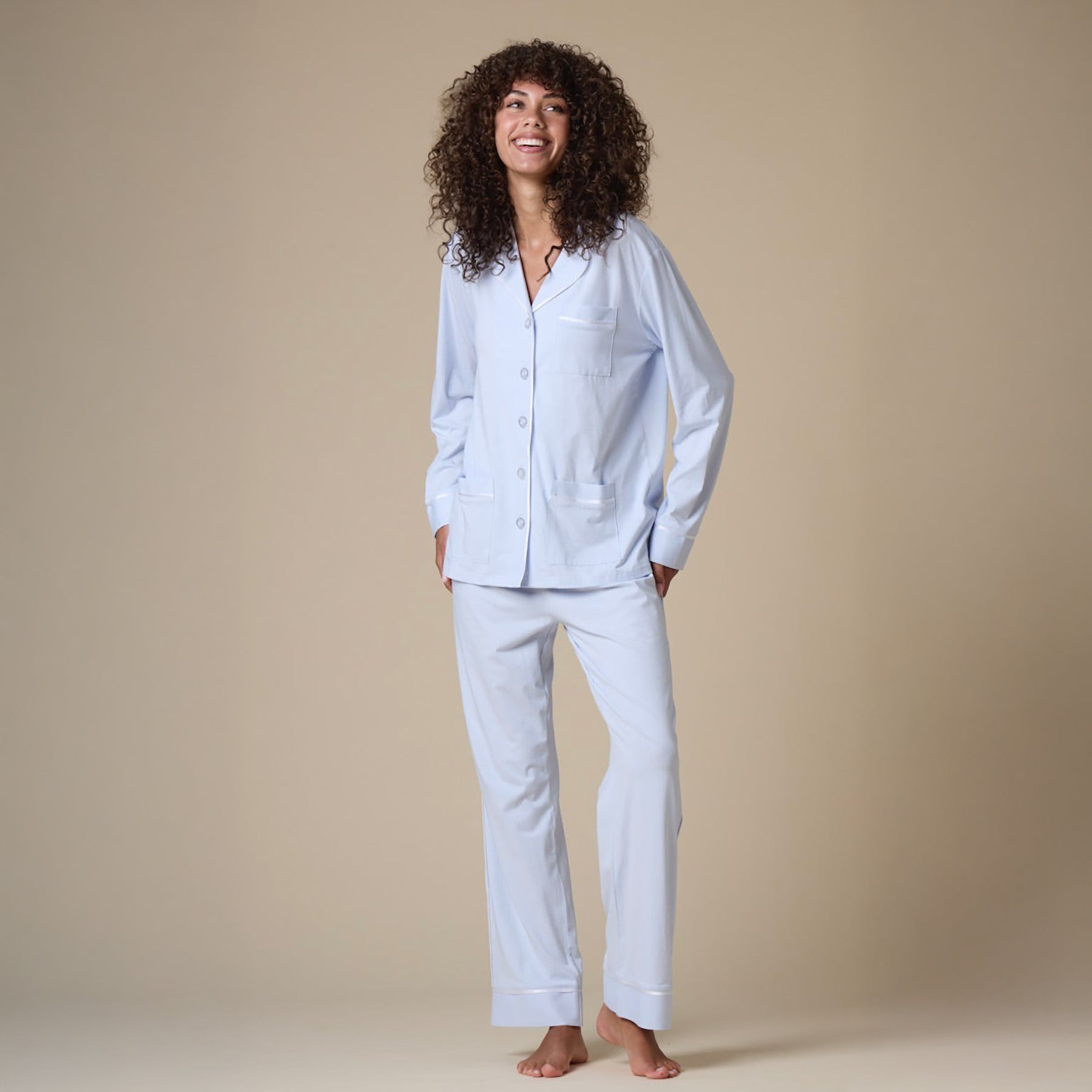 Classic cotton button up pyjama set in baby blue with contrast white piping. Front view on model.