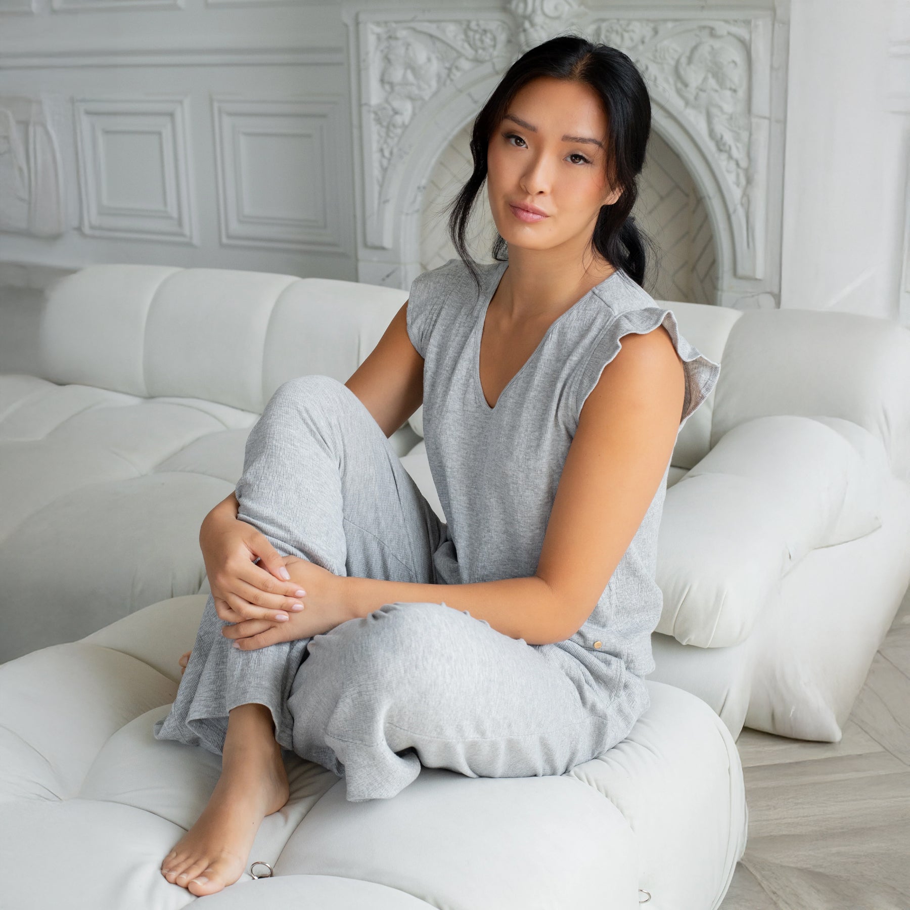 Light grey relaxed lounge set styled on model seated on sofa, showcasing soft drape and all-day comfort