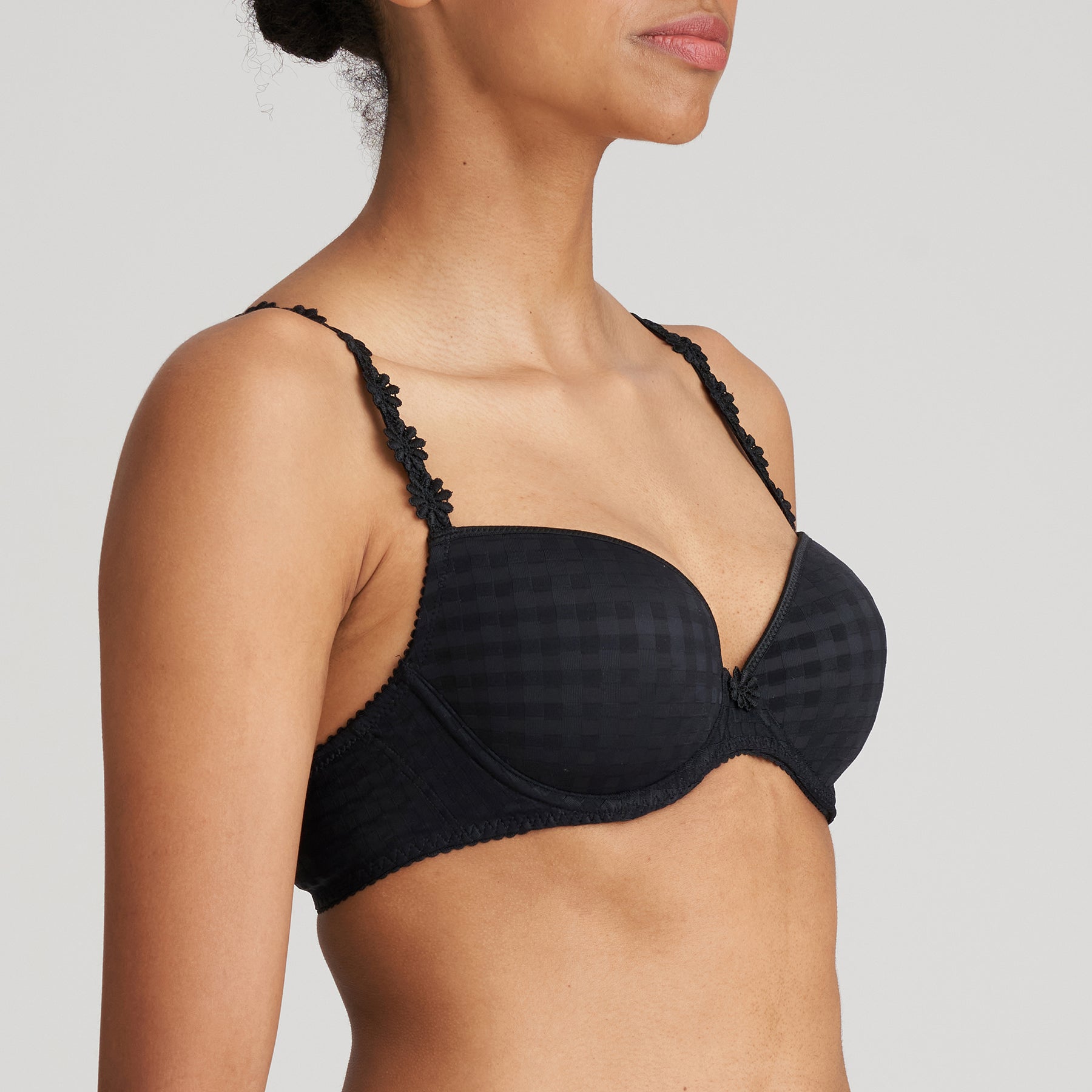 Padded plunge bra in black with checkerboard print and embroidered daisy straps. Side view on model.