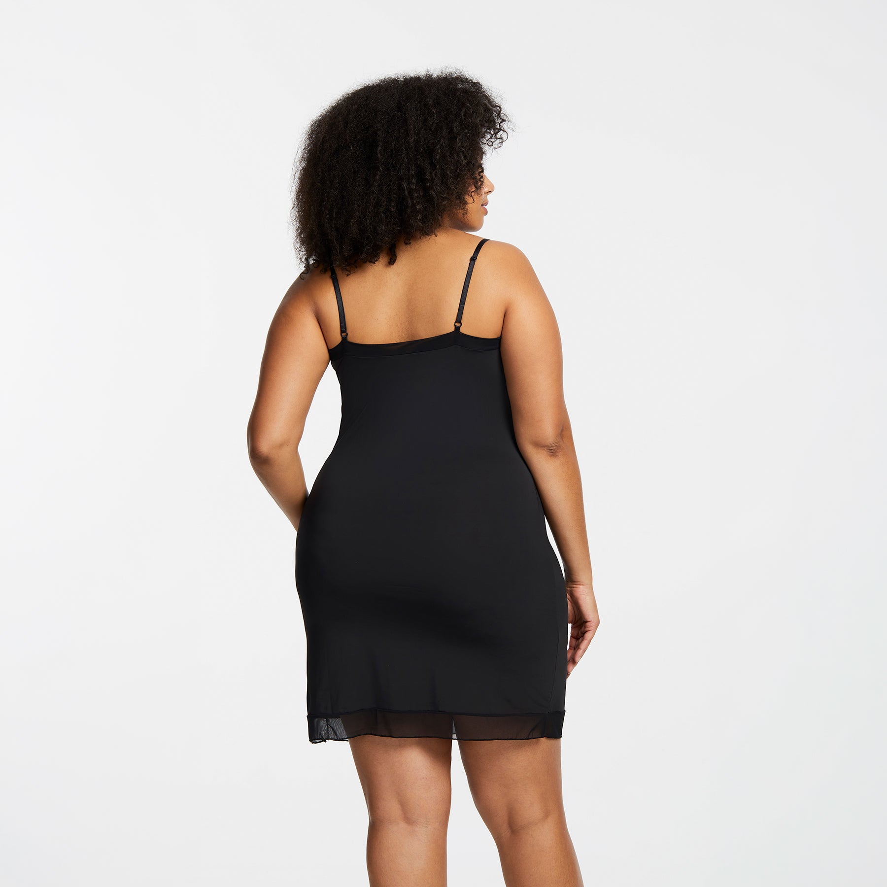 Montelle Intimates 9500 V-neck slip at knee in Black colour with sleek invisible silhouette and sheer hem, angled back view on curvy model.