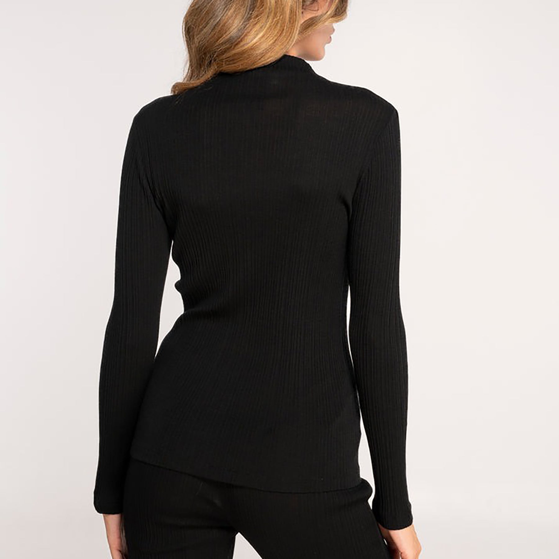 long sleeve ribbed funnel neck top in black made of wool and silk. Rear view on model.