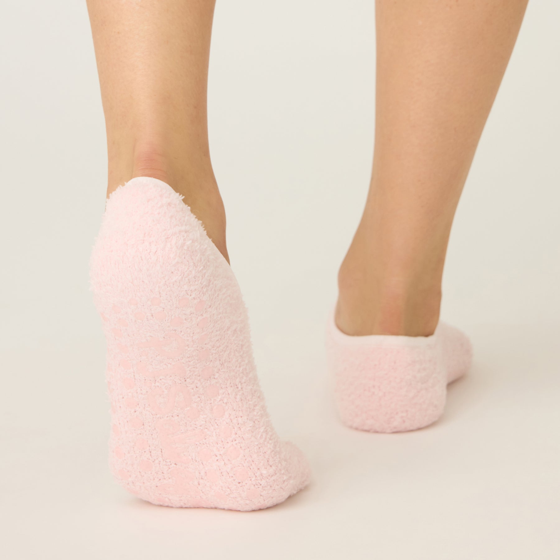 Pink fuzzy socks worn by a person on a light background