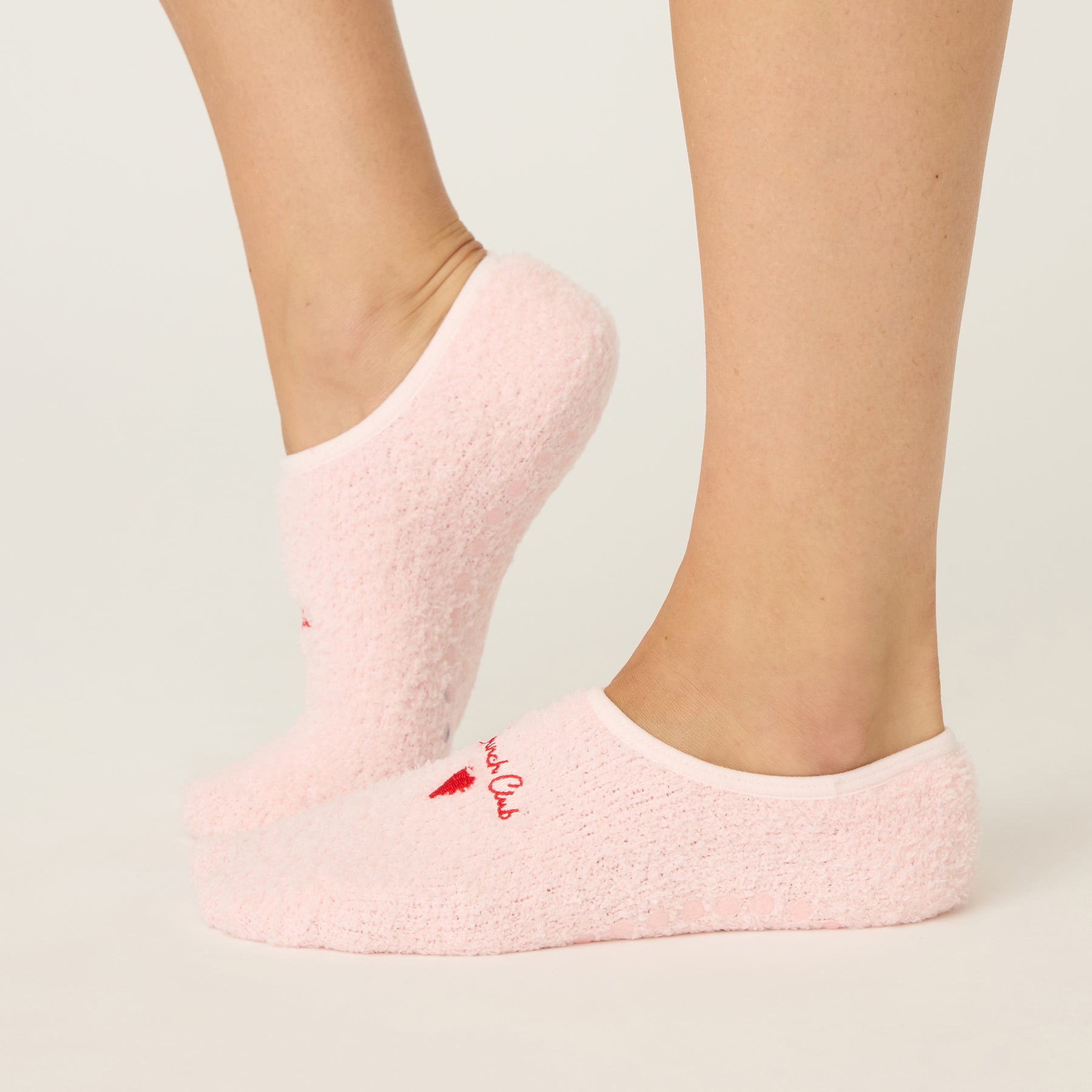 Pink socks with a brand logo worn by a person on a light background