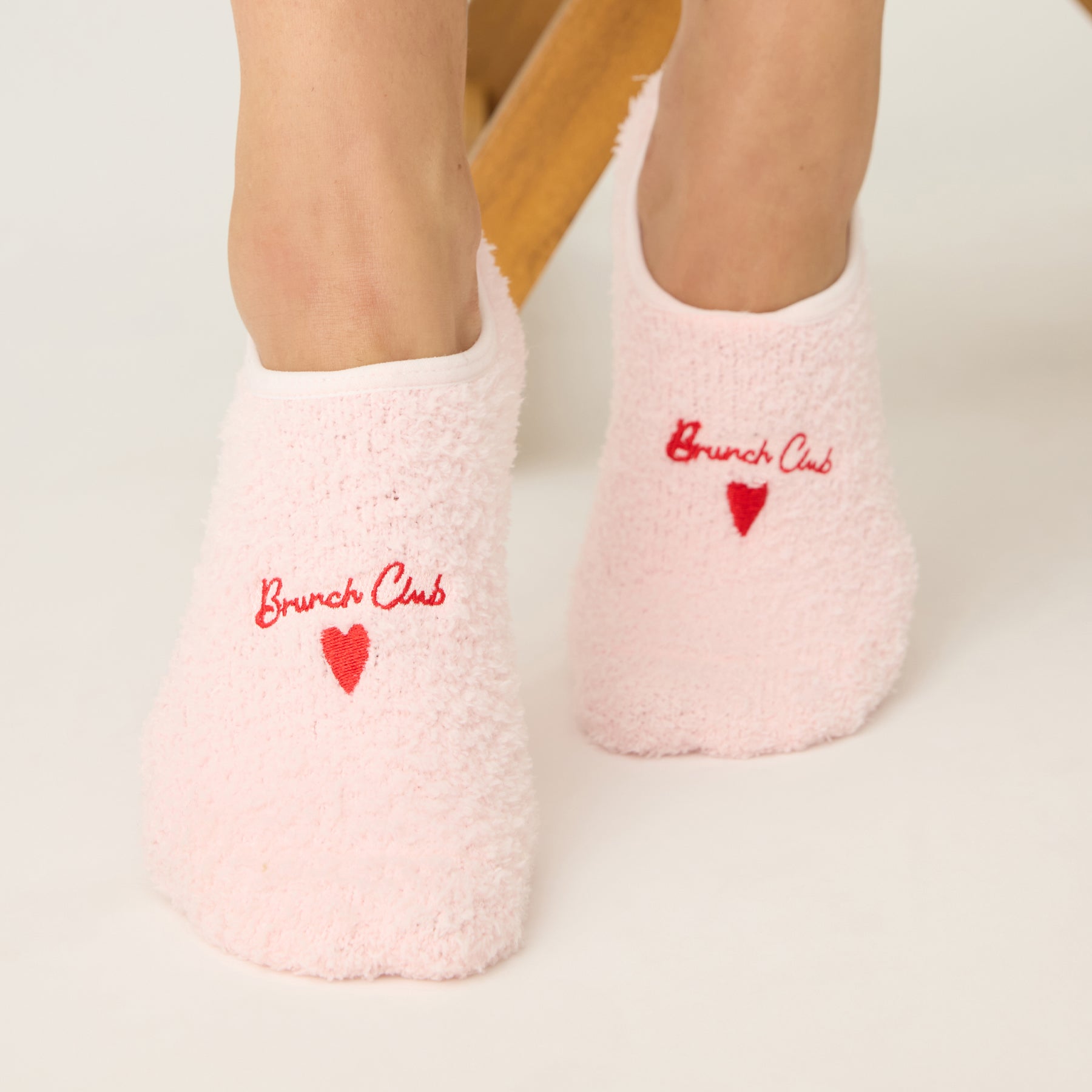 Pink socks with 'Brunch Club' and heart designs on a light background
