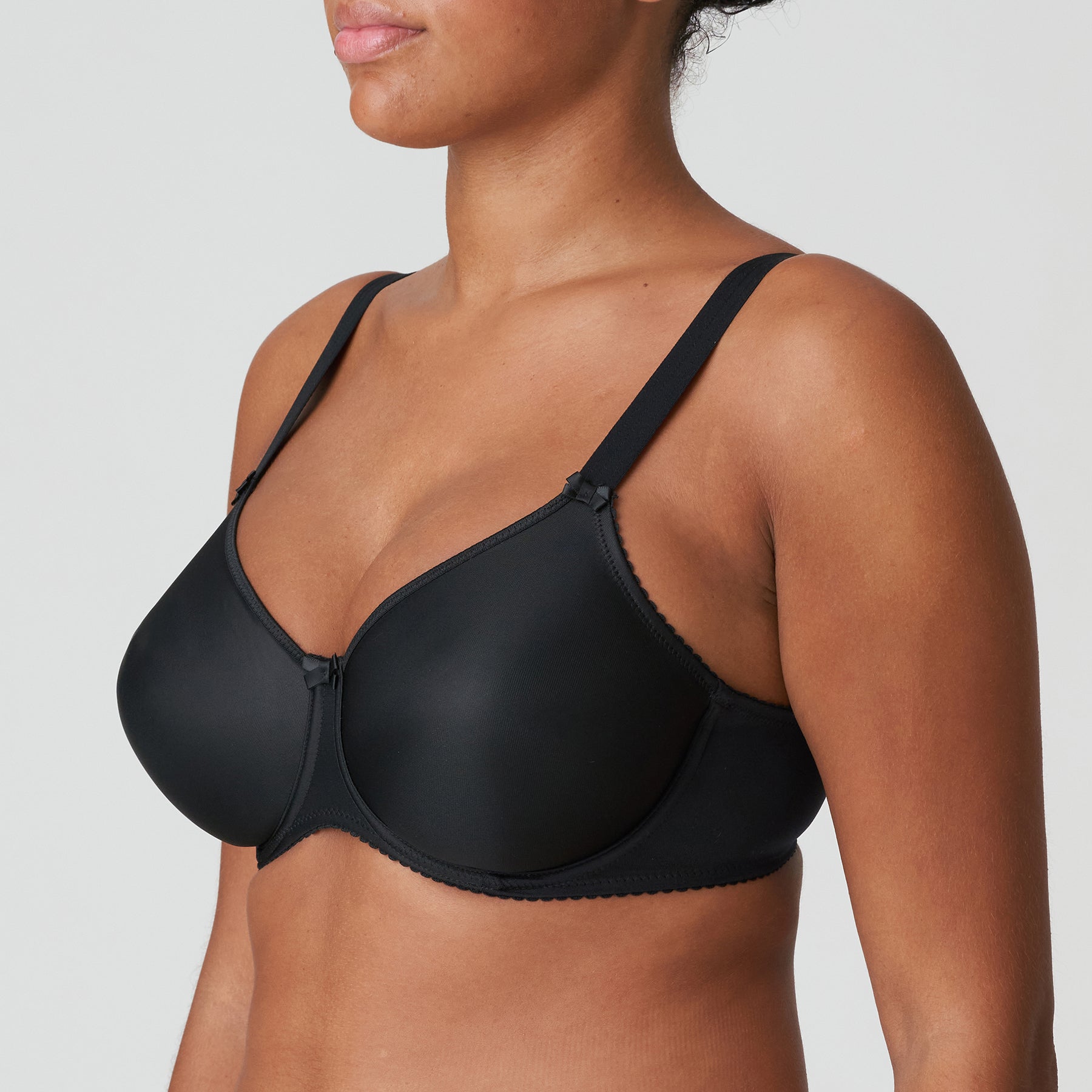 Seamless underwired black bra. Side view on model.