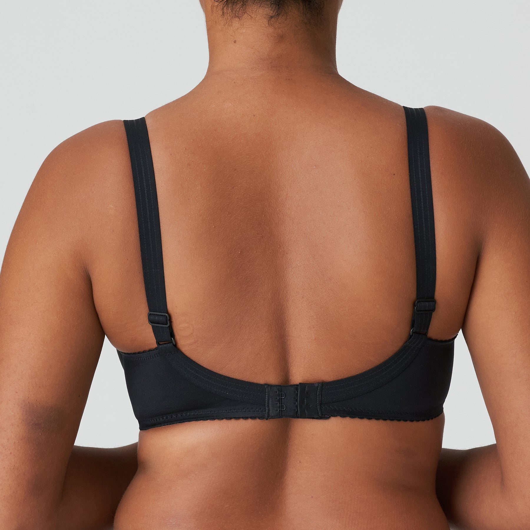 Seamless underwired black bra. Rear view on model.