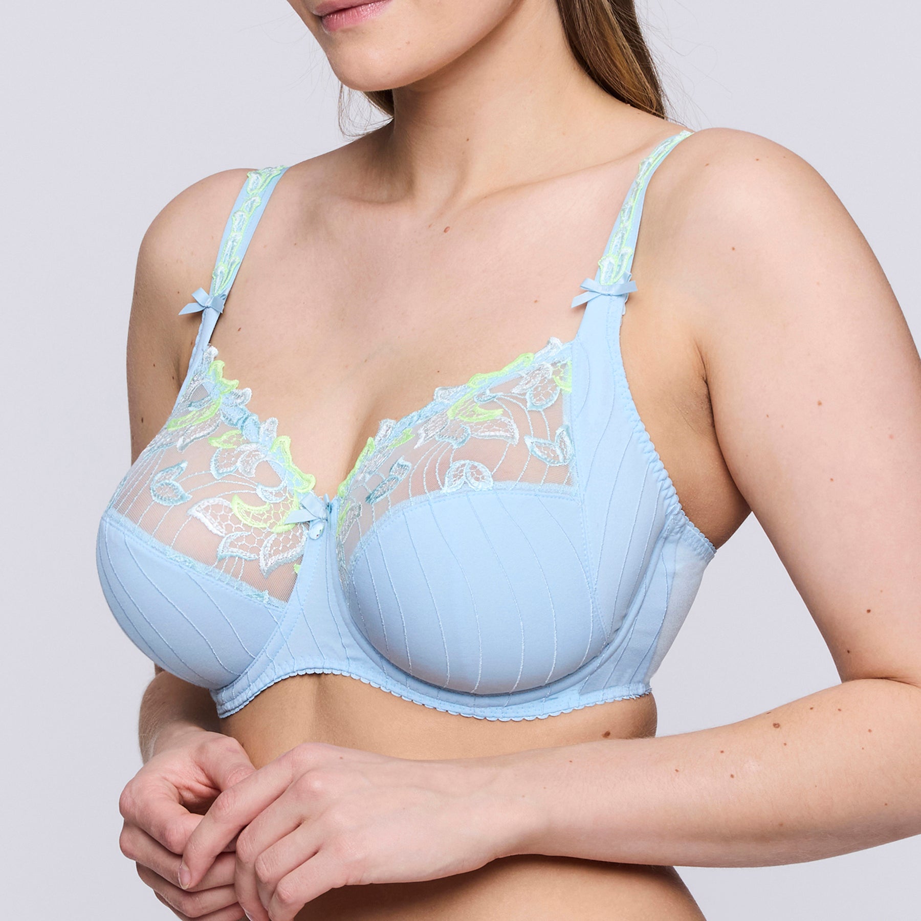 Full cup underwired bra in milky baby blue with contrast lime green embroidery on upper cups. Side view on model.