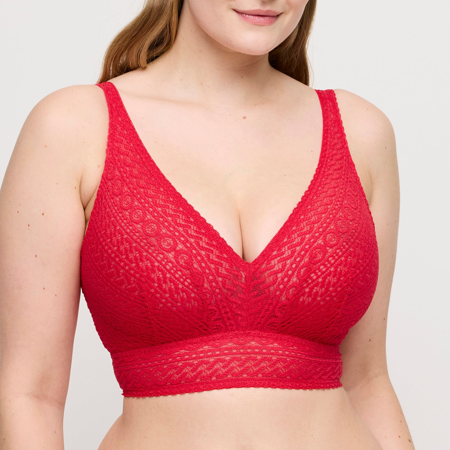 Model wearing PrimaDonna Montara wireless plunge bra in true red with soft stretch lace, deep V neckline, and supportive longline band front view