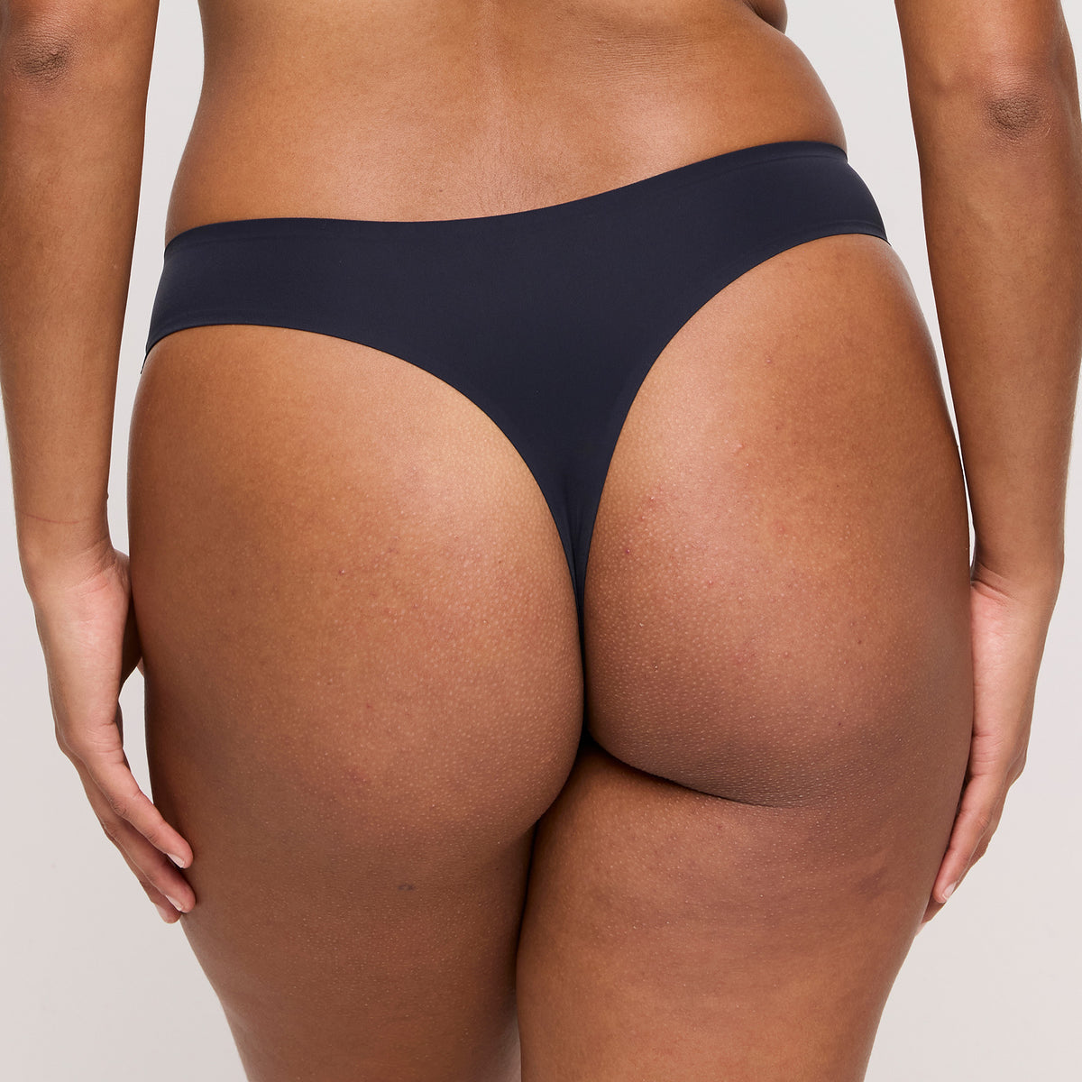 Back view of model wearing PrimaDonna Figuras Seamless Thong Style 0663250 in Charcoal, highlighting minimal thong coverage, a smooth waistband, and seamless edges for an invisible finish under clothing.
