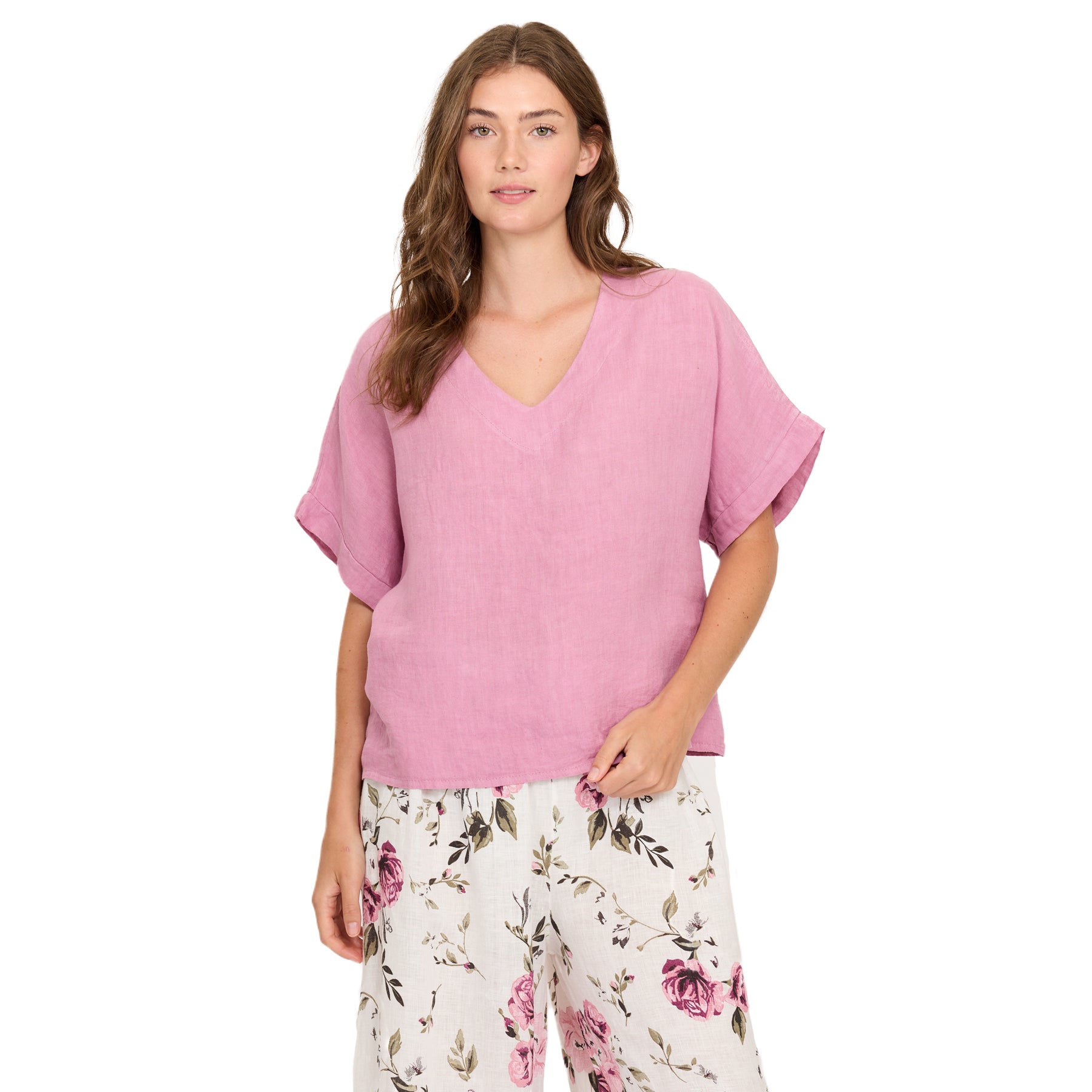 Woman wearing peony pink linen blouse with V-neck and rolled sleeves styled with floral trousers
