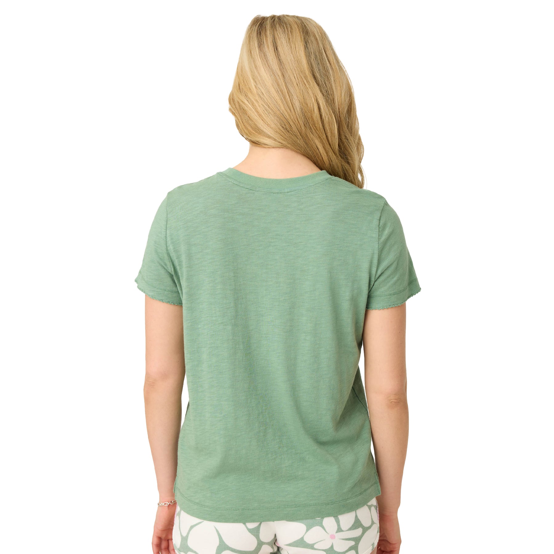 Back view of woman wearing light green short-sleeve cotton T-shirt and printed shorts.