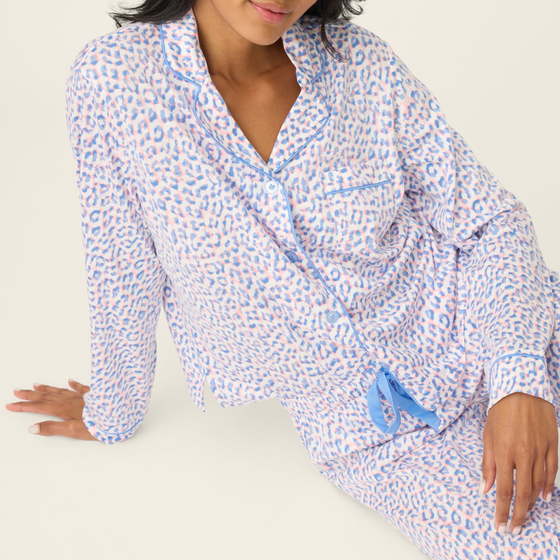 Close-up of bluebird leopard print pyjama top with notched collar, contrast piping, chest pocket, and button-front detail