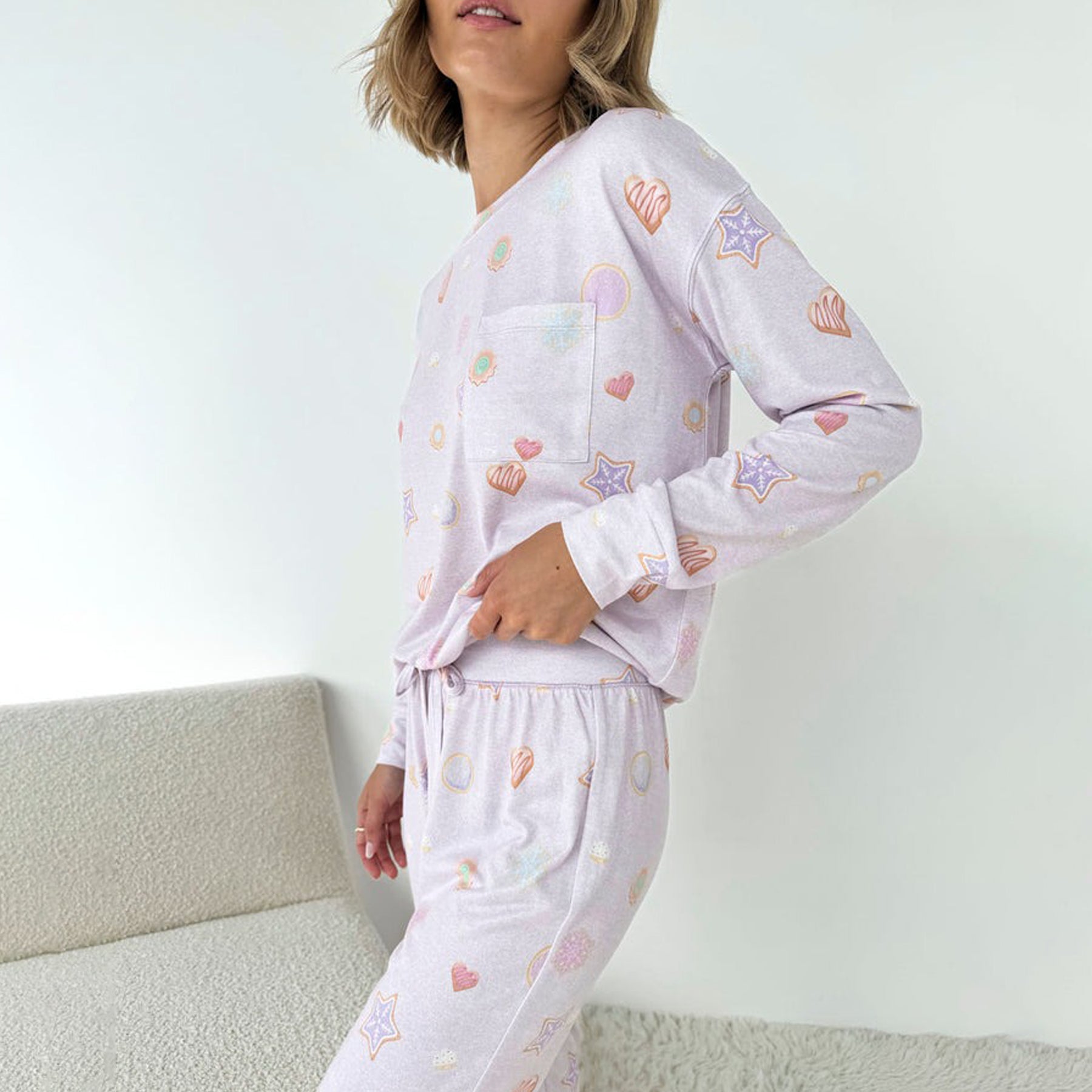 Side view of woman in lilac printed pajamas featuring stars and hearts.