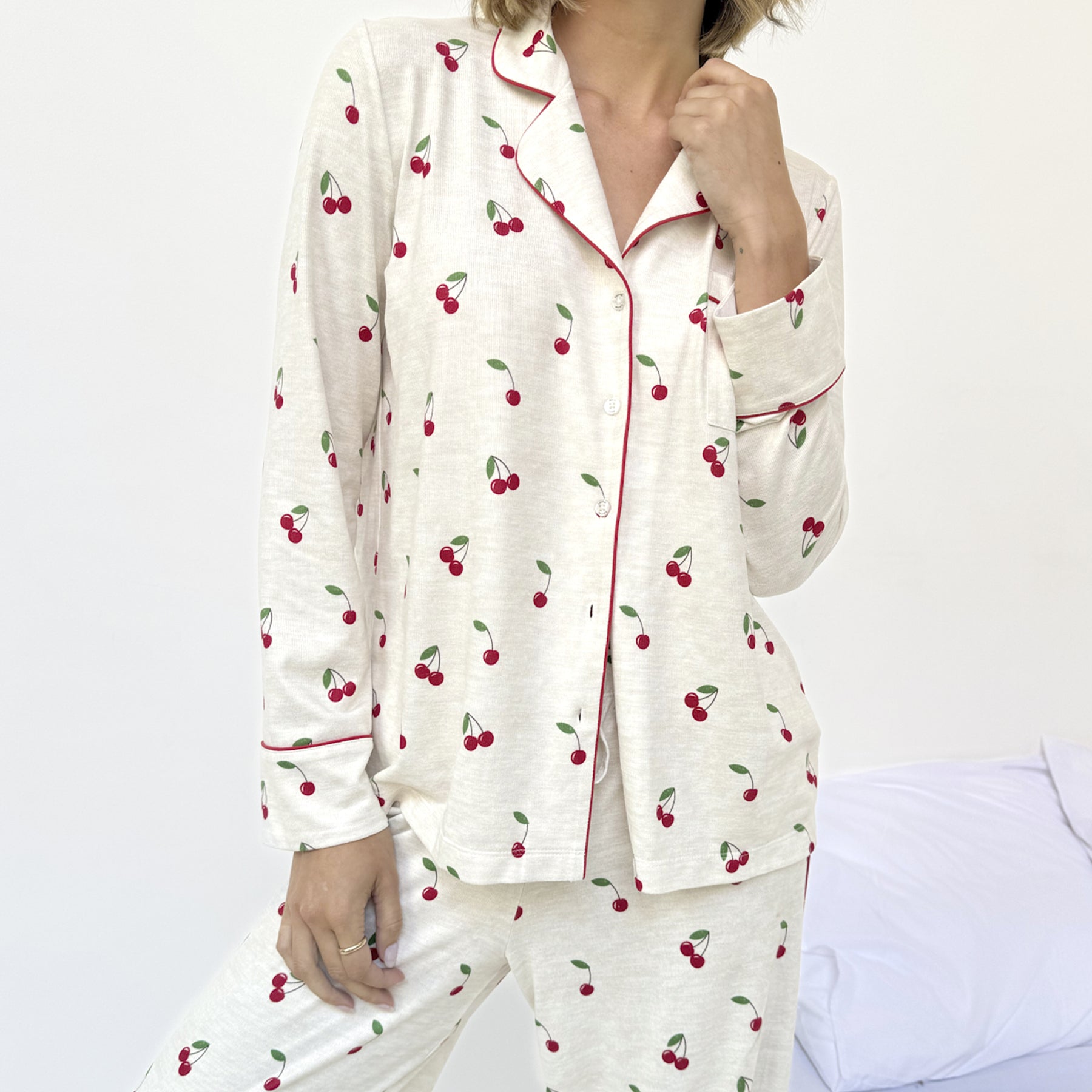 Close-up of cherry print pyjama top with red piping and front pocket detail.