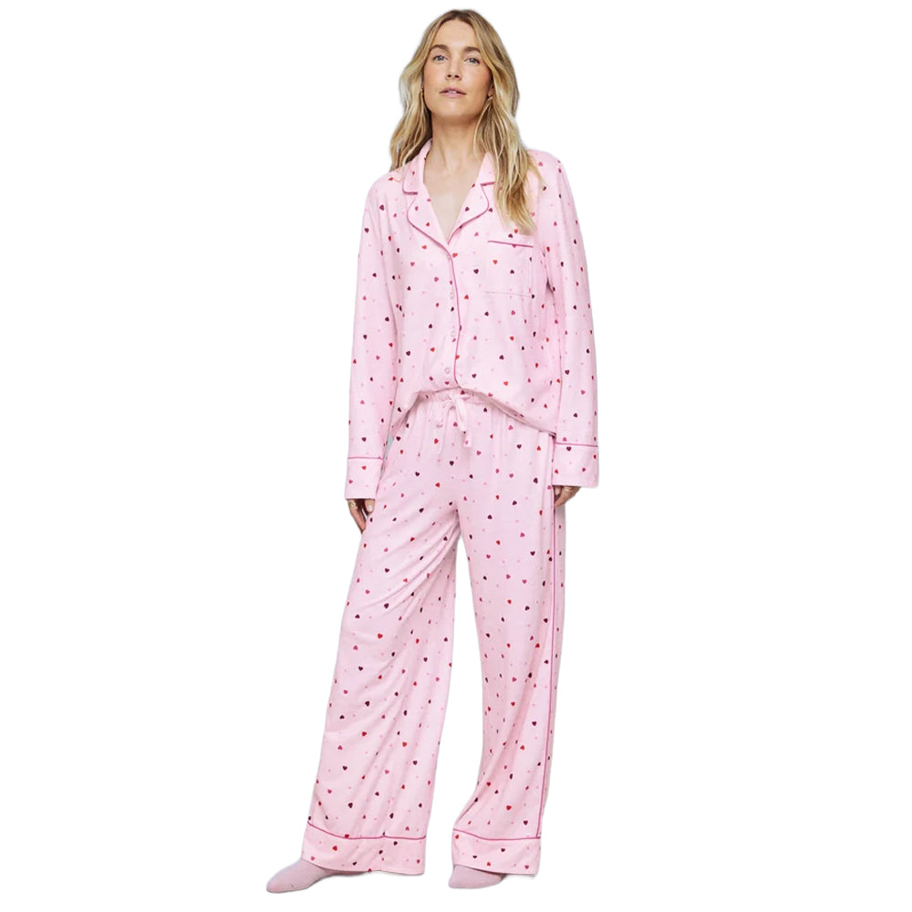 Model wearing Splendid Pillowsoft pink heart print PJ Set with button-up long-sleeve shirt, drawstring waist, and relaxed wide-leg pajama pants.