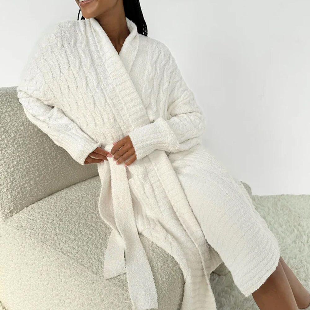 Splendid ivory plush knit robe featuring a shawl collar, long sleeves, waist tie belt, and textured fabric, worn by a model relaxing on a cozy sofa.