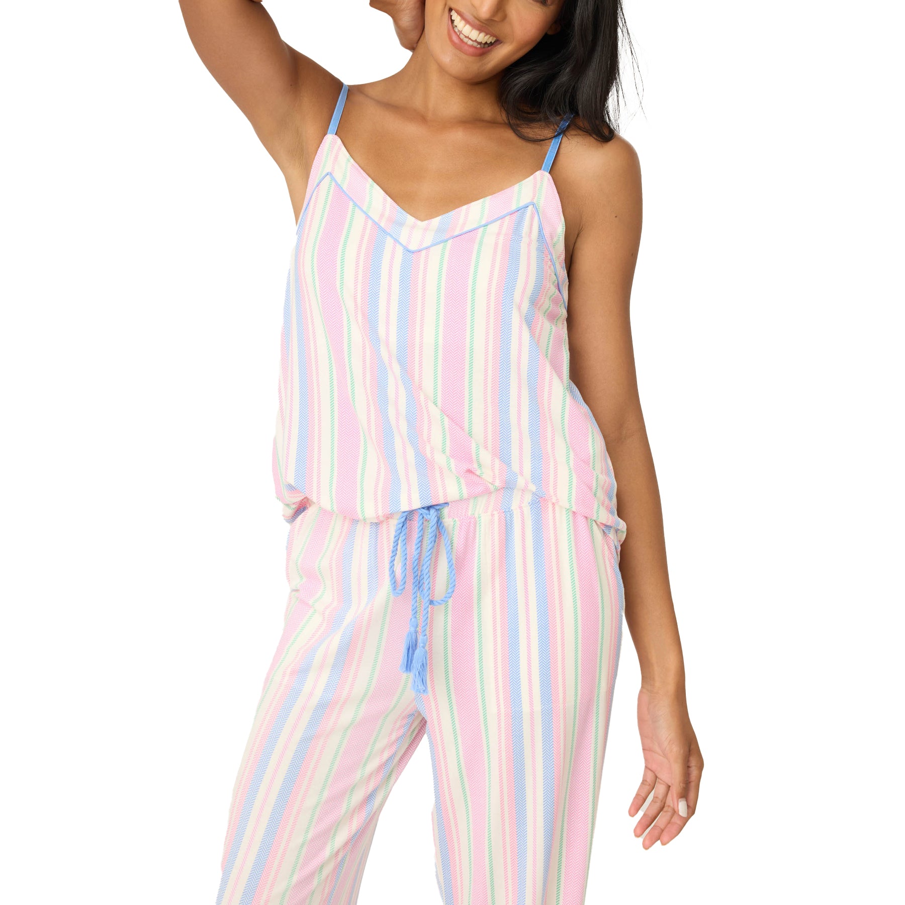 Woman standing in pastel striped sleep set, smiling, with adjustable blue spaghetti straps and elastic drawstring waistband.