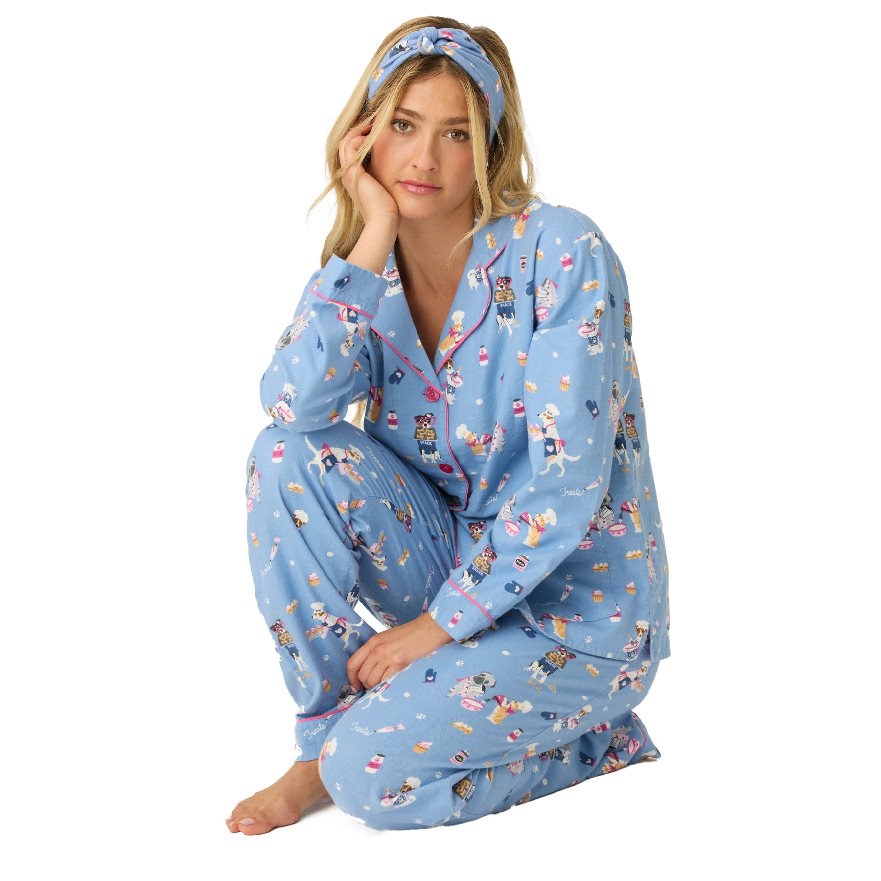 Woman wearing blue flannel pajama set with playful dog baking print, button-up top, and matching pants with headband.