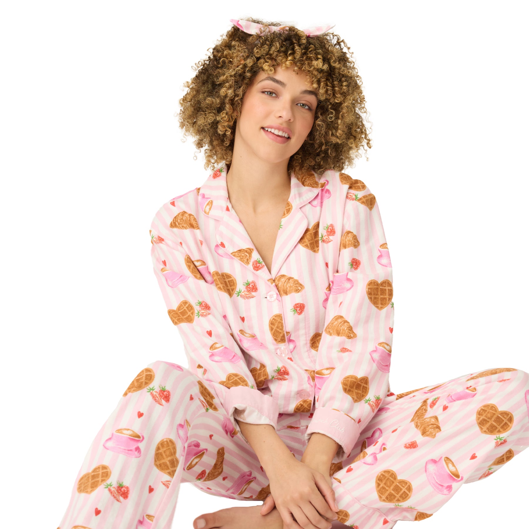 Woman sitting in pink striped breakfast-print pajama set.
