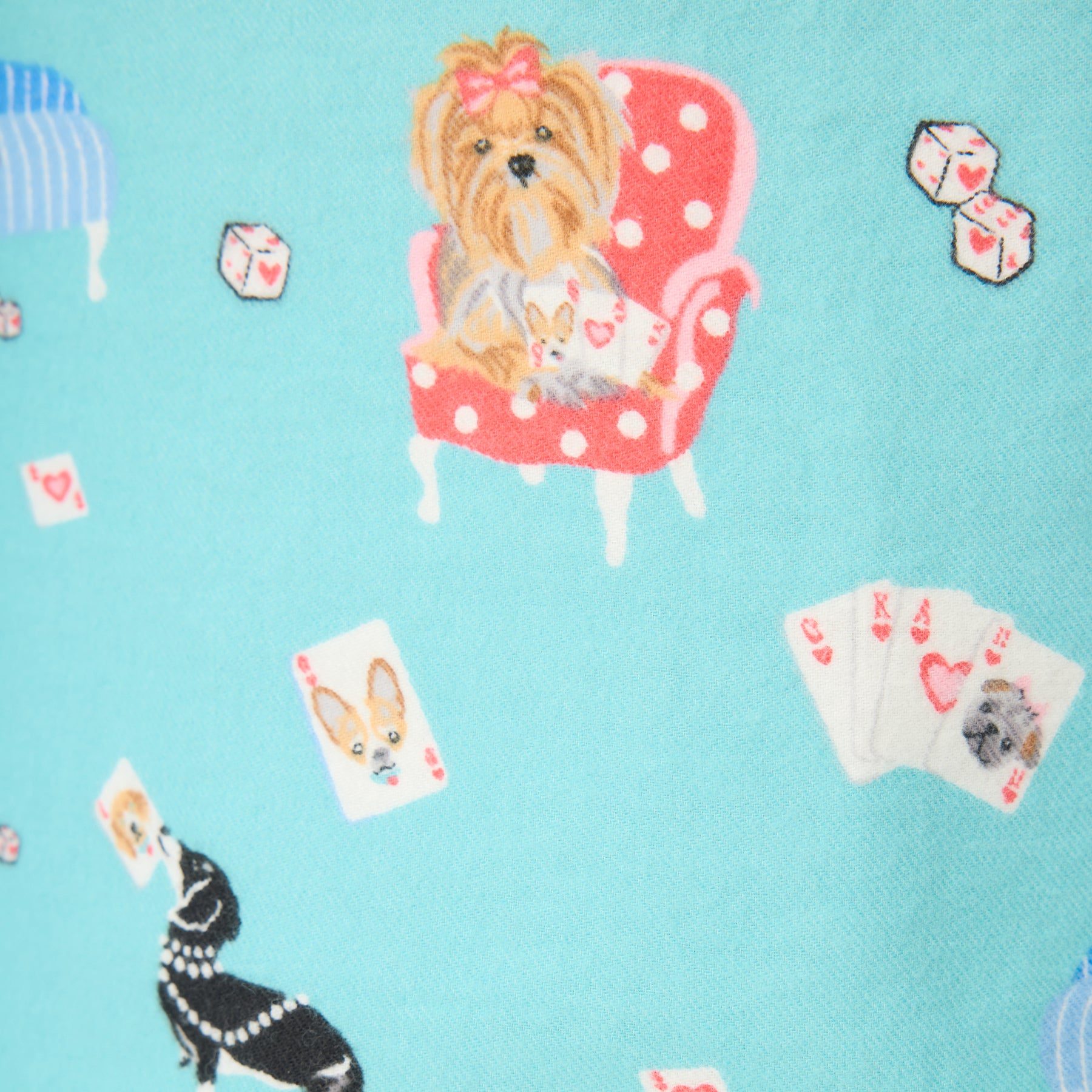 Close-up of turquoise pajama fabric with dogs, dice, and playing cards.