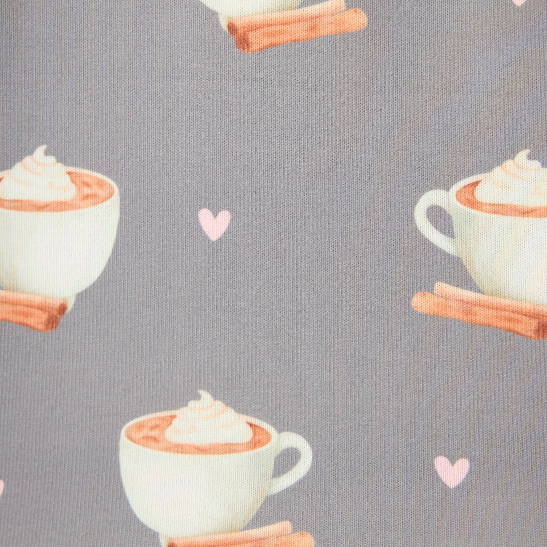 Fabric close-up showing mugs of hot cocoa with whipped cream and cinnamon sticks on grey background.