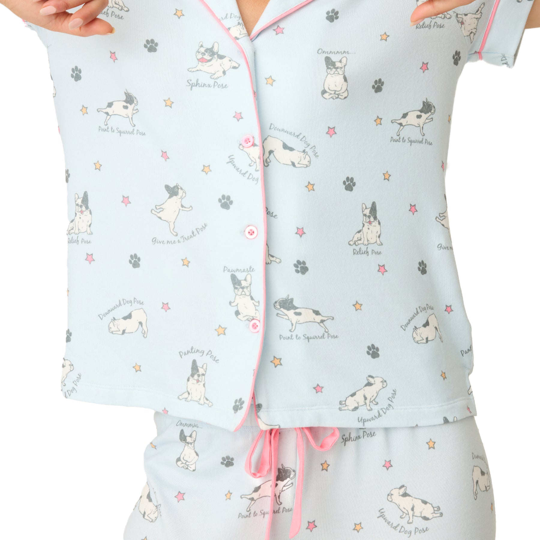 Detailed view of the pyjama top’s front showing cartoon dog illustrations, pink buttons, and pose names.