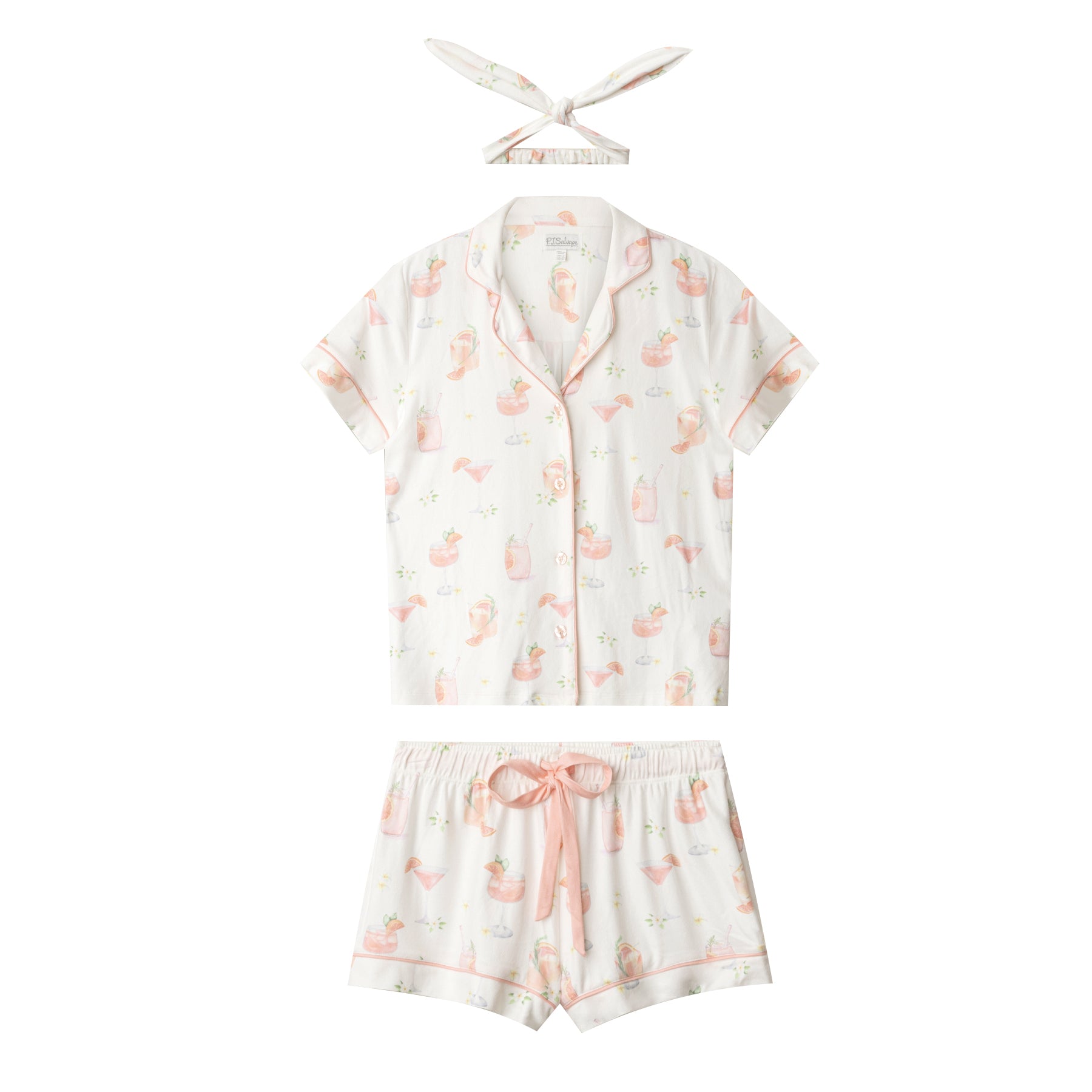 Flat lay of ivory cocktail-print pyjama set with short sleeve top, drawstring shorts, and matching headband