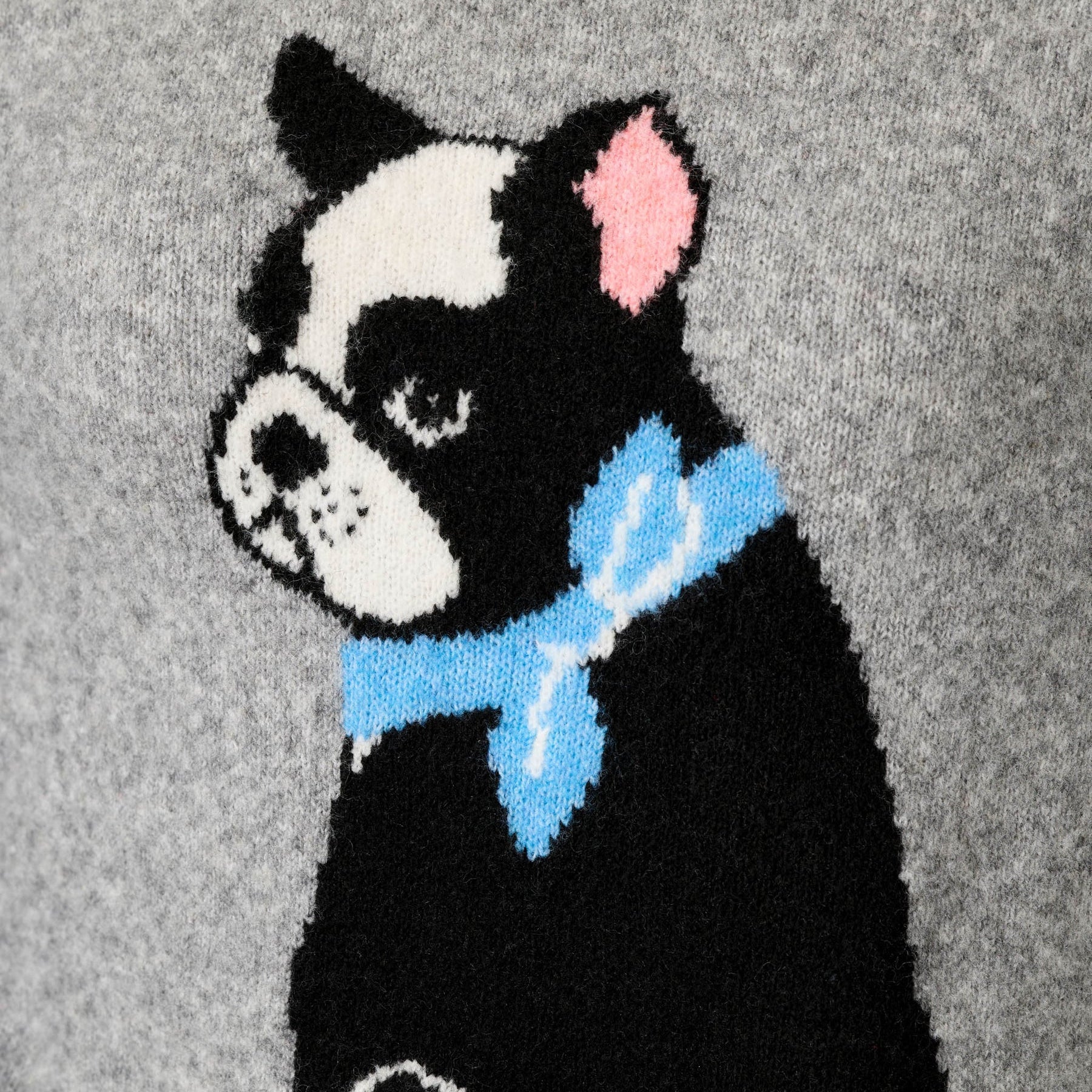 Close-up of a knitted sweater featuring a black and white Boston Terrier dog wearing a light blue bow tie, set against a heather gray background.